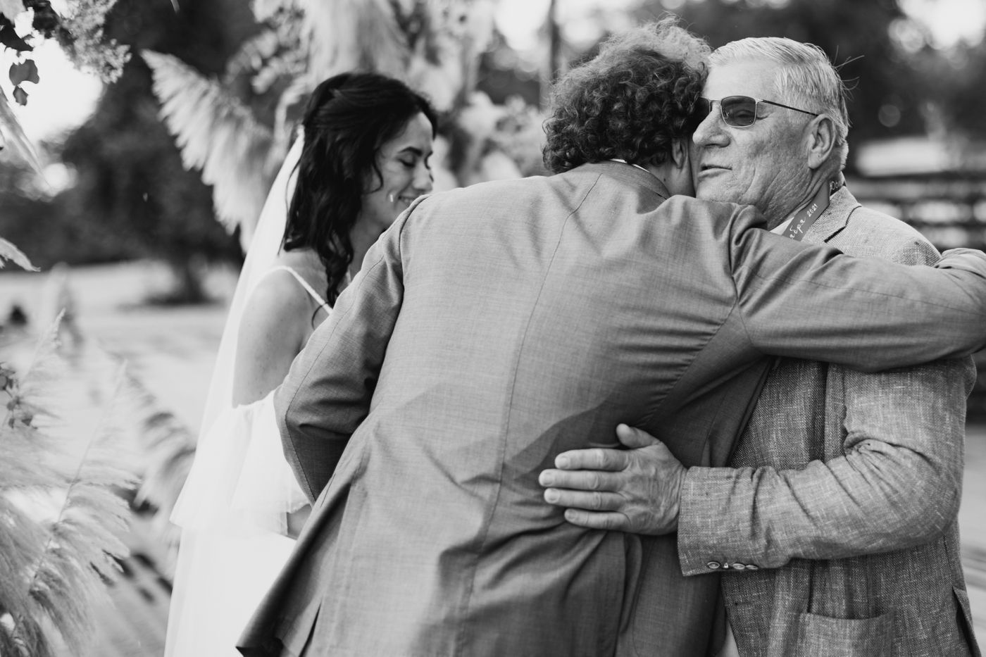 A black and white candid photograph of people embracing outdoors in a tender moment.