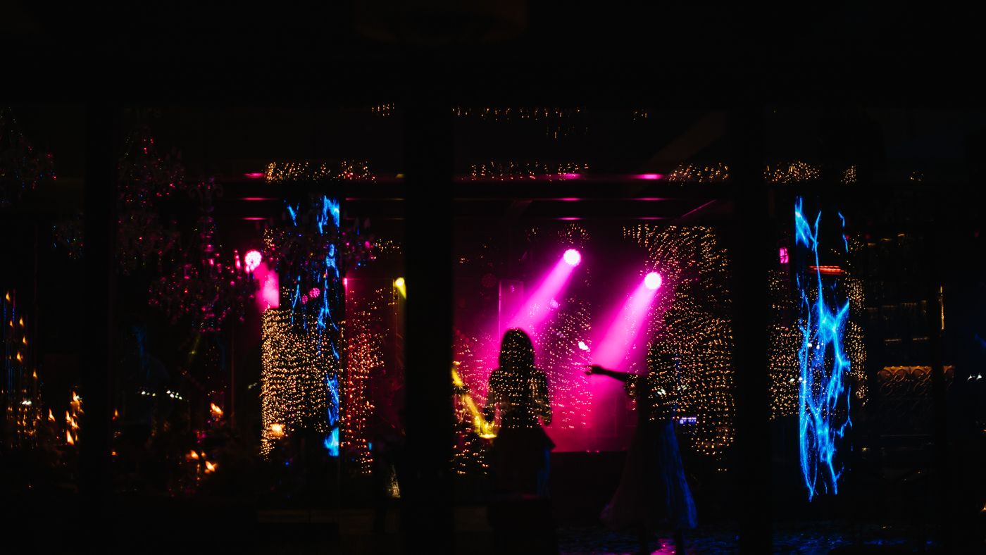 Dark concert venue illuminated with colorful stage lighting and special effects.