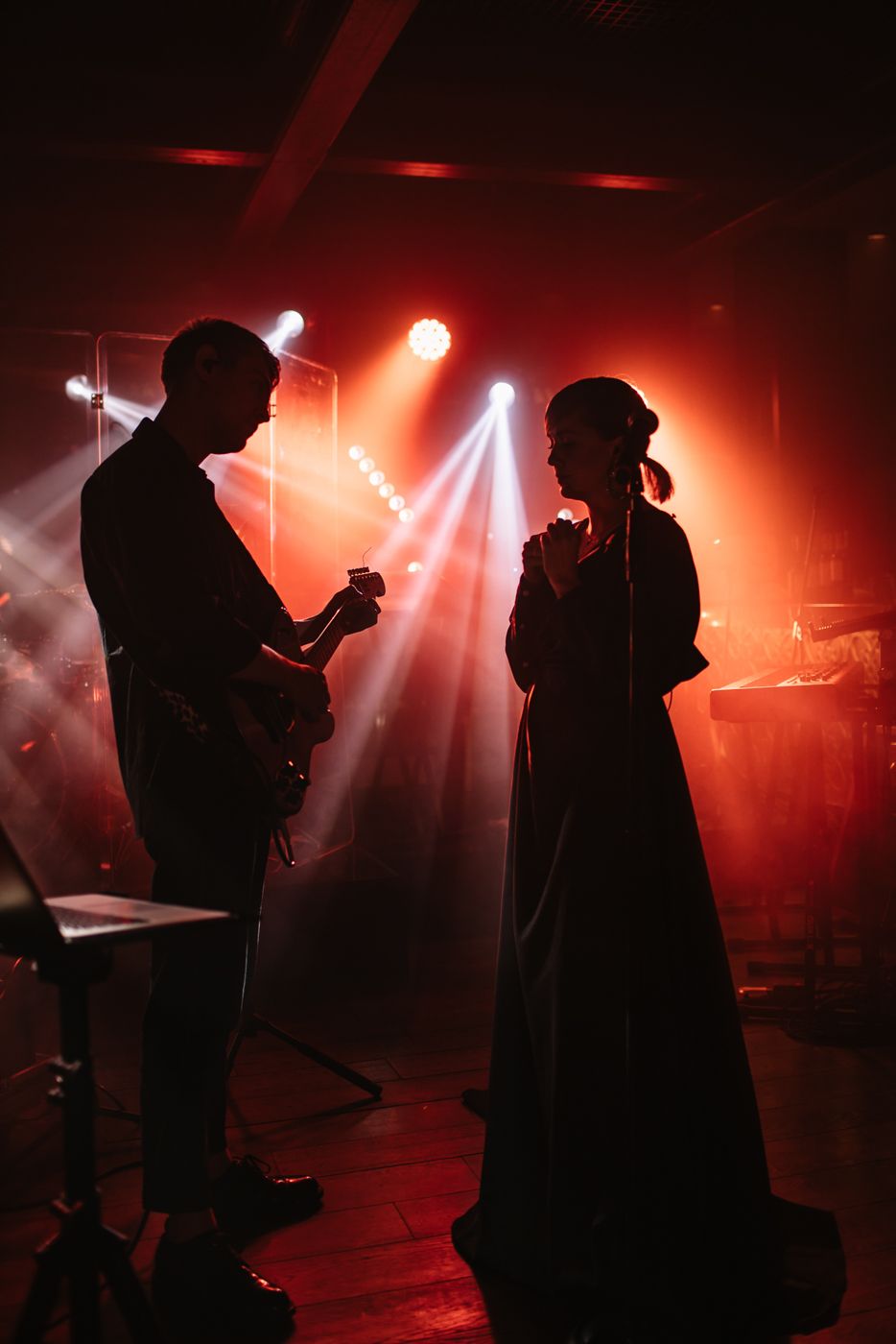 Band performs on stage with dramatic red lighting and fog effects.