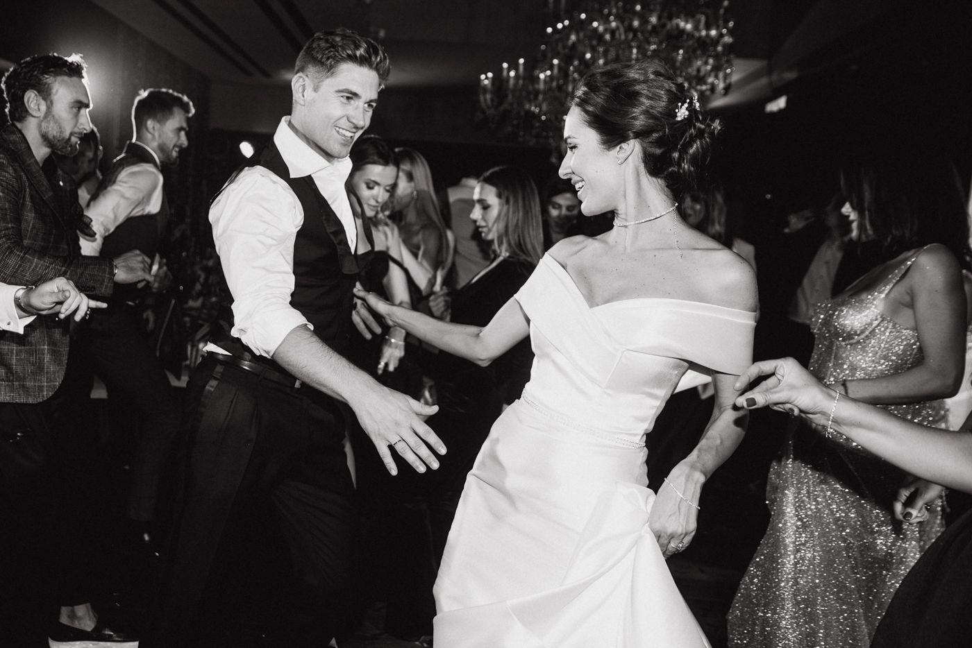 Wedding celebration with guests dancing in black and white photography.