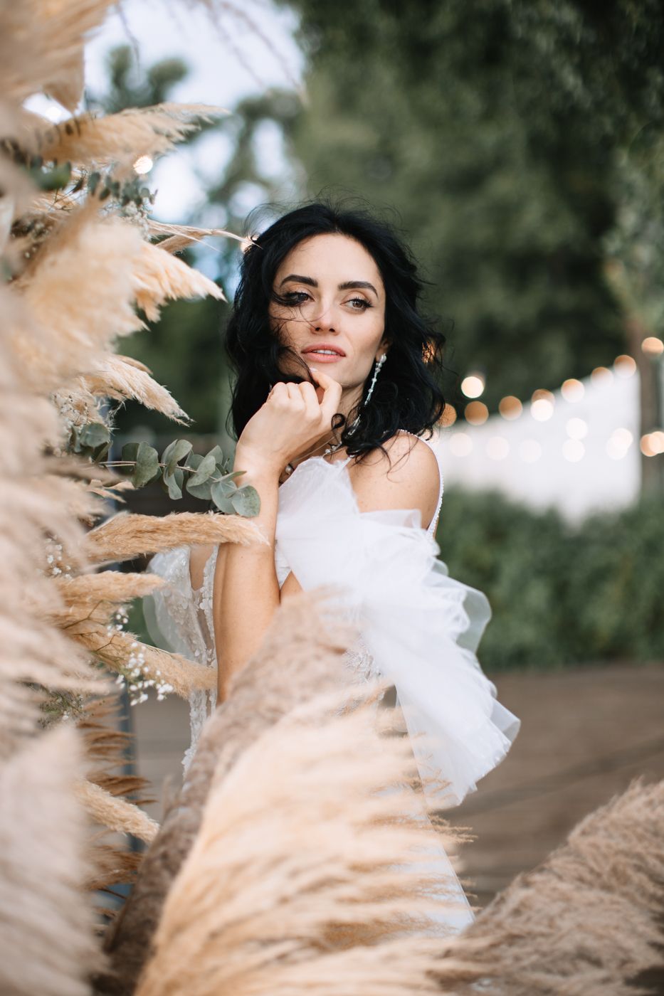 Dreamy outdoor portrait featuring a white flowy dress against natural pampas grass and bokeh lighting effects.