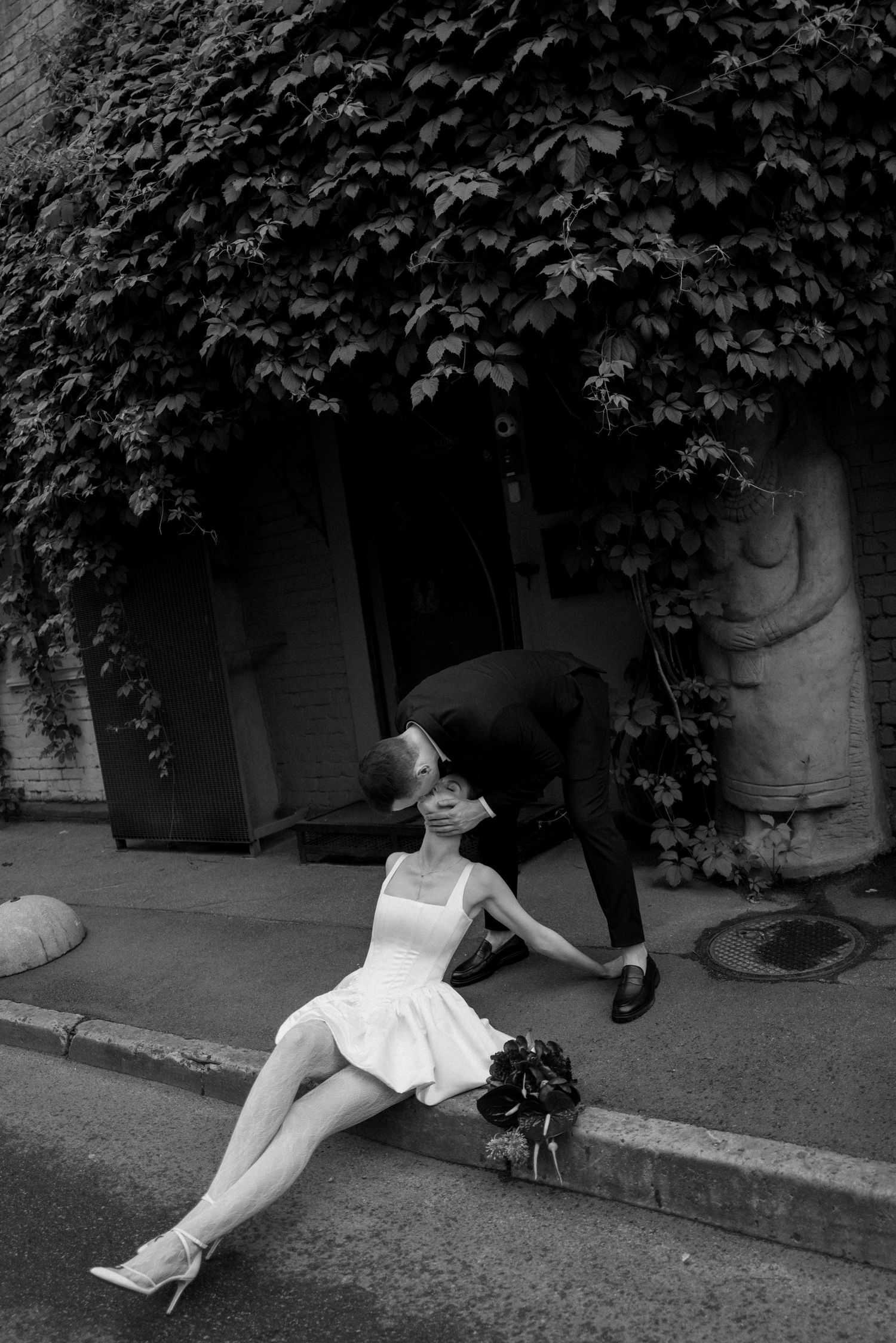 A sequence of black and white photos shows a figure in a white dress falling down on a city sidewalk.