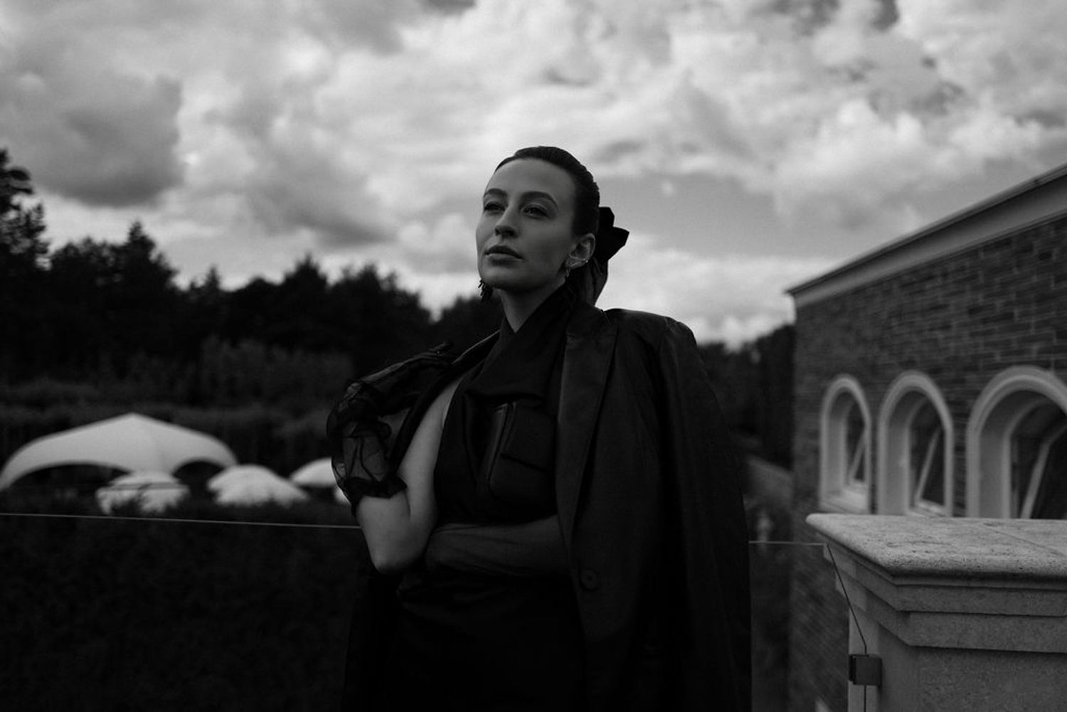 A dramatic black and white photo montage showing six different artistic portrait shots against cloudy skies.