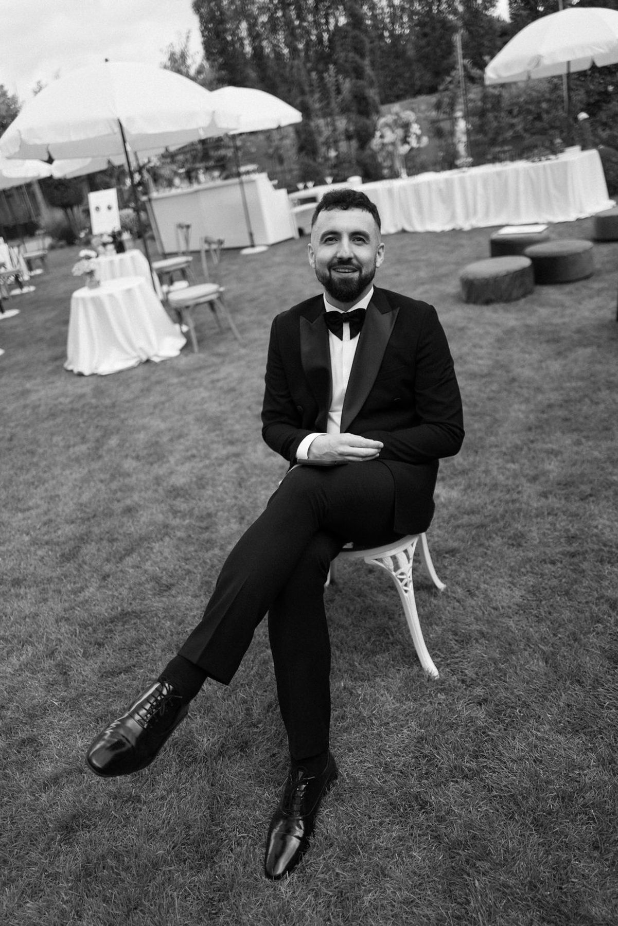 A sequence of black and white photos showing someone in a suit sitting on grass at an outdoor event.