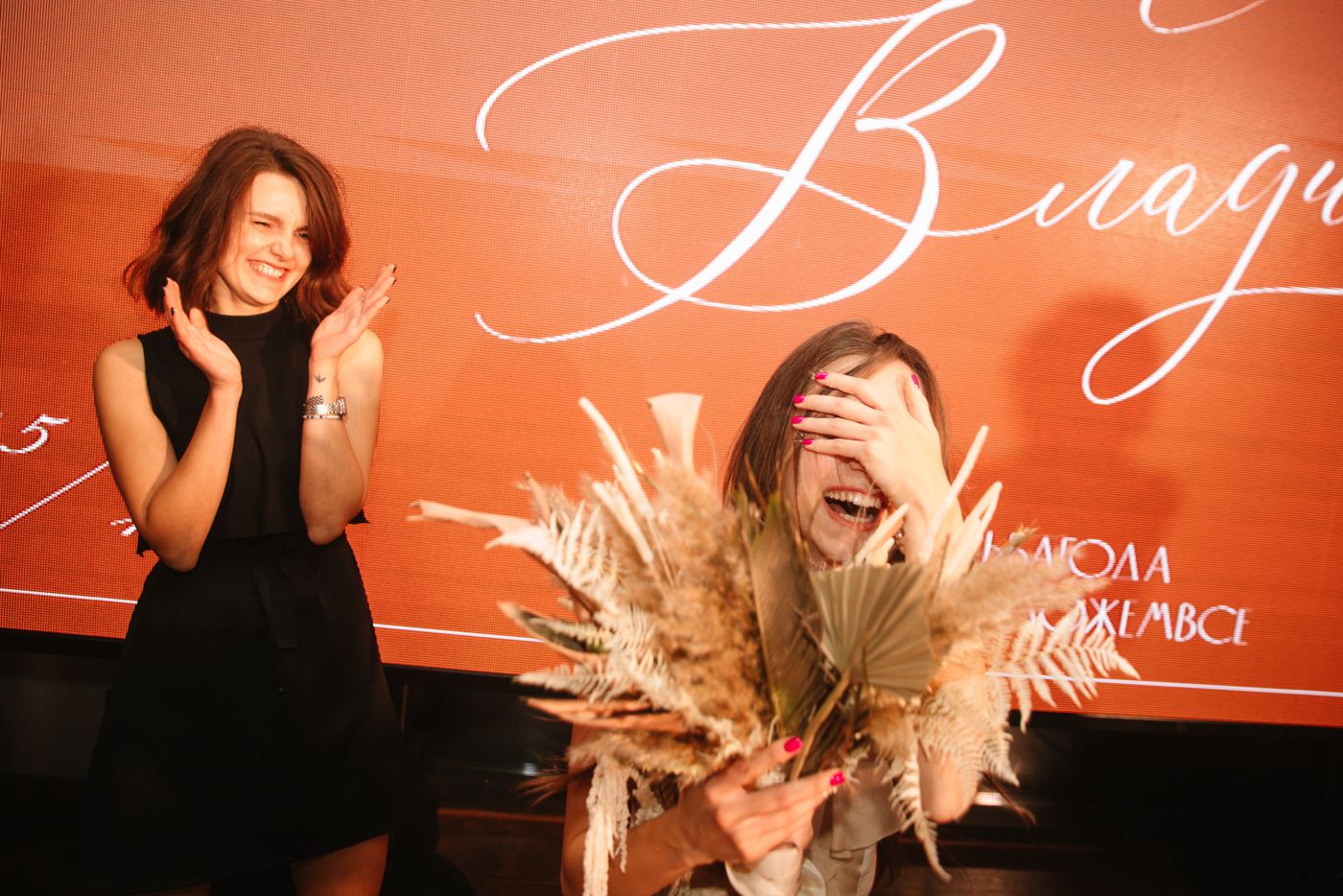 Wedding reception venue with elegant orange lighting and cursive text decoration.