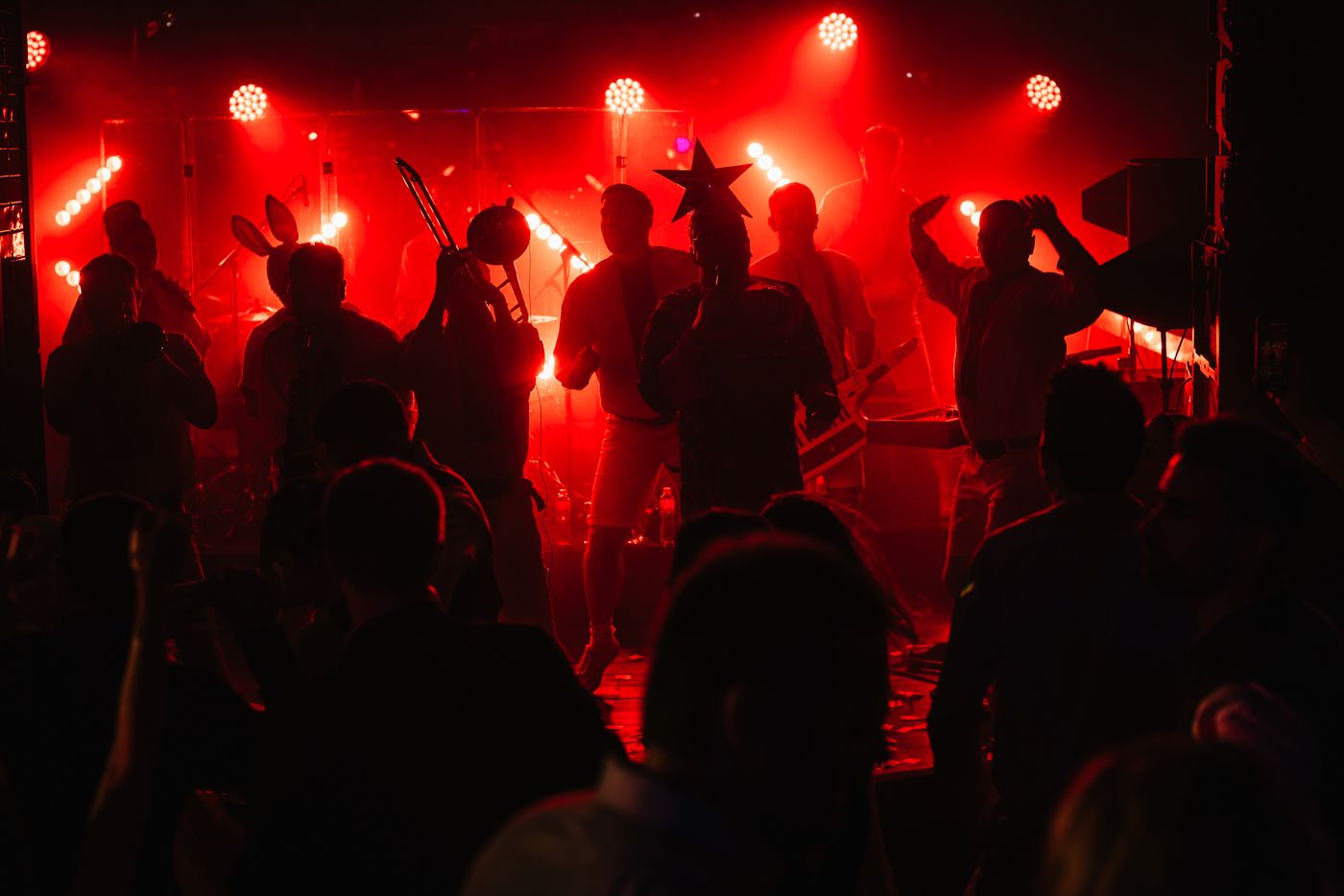 Concert crowd silhouettes against bright red stage lighting at a live performance.