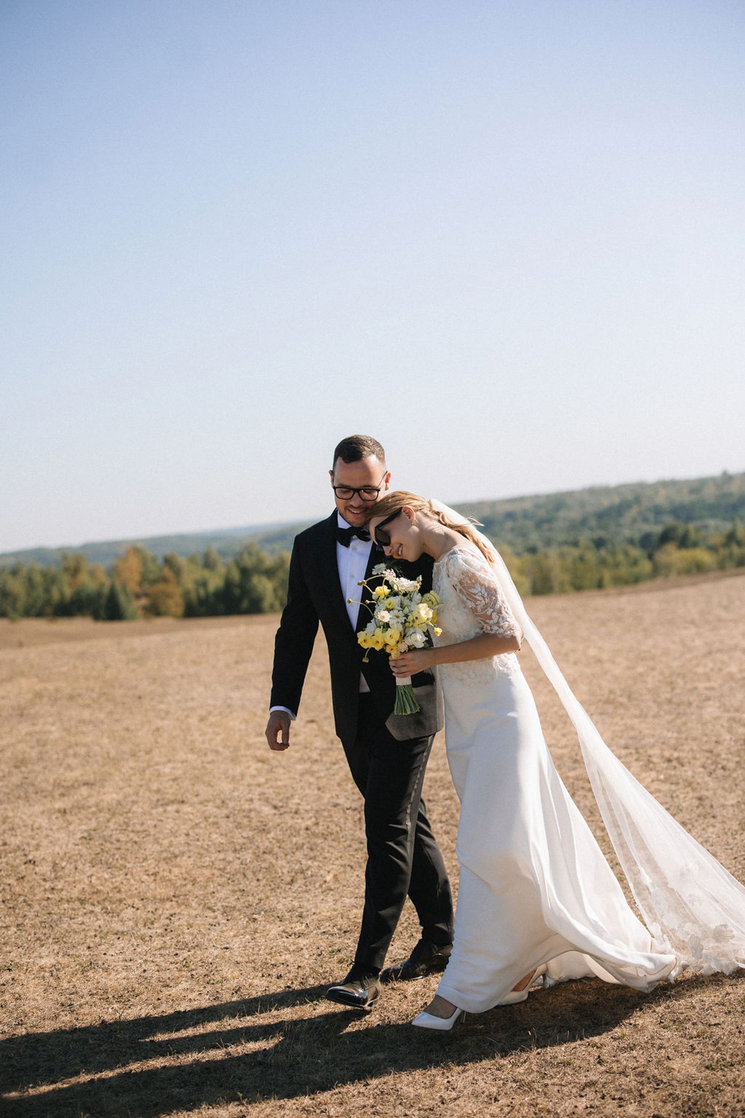 A couple in wedding attire shares a romantic moment in a golden field on their special day.