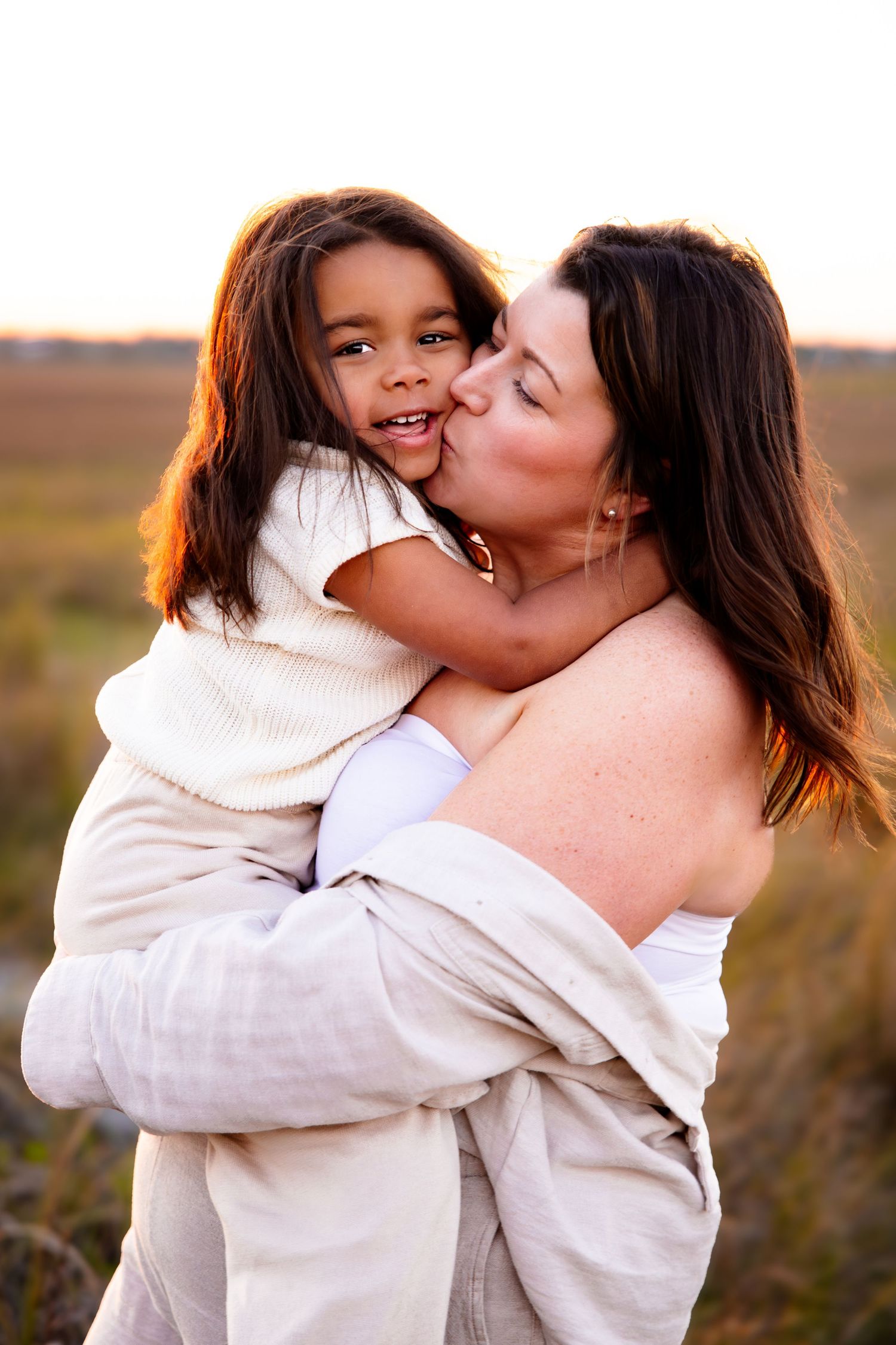 Tender moment between parent and child captured in warm sunset lighting.