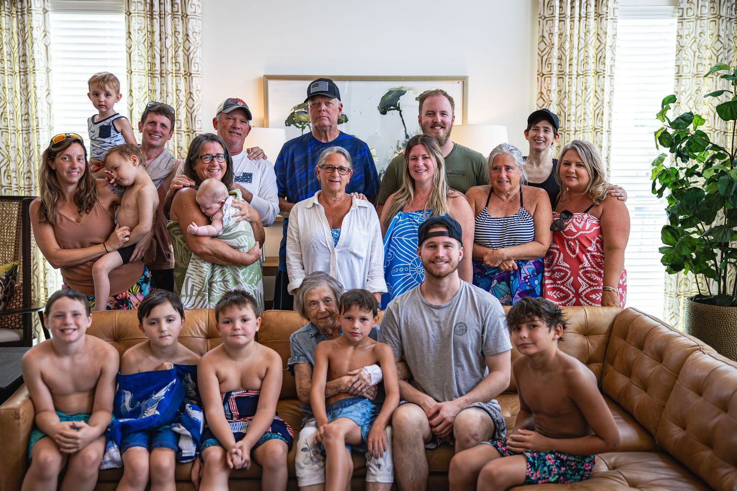 Large extended family gathering poses together on a couch in a living room setting.