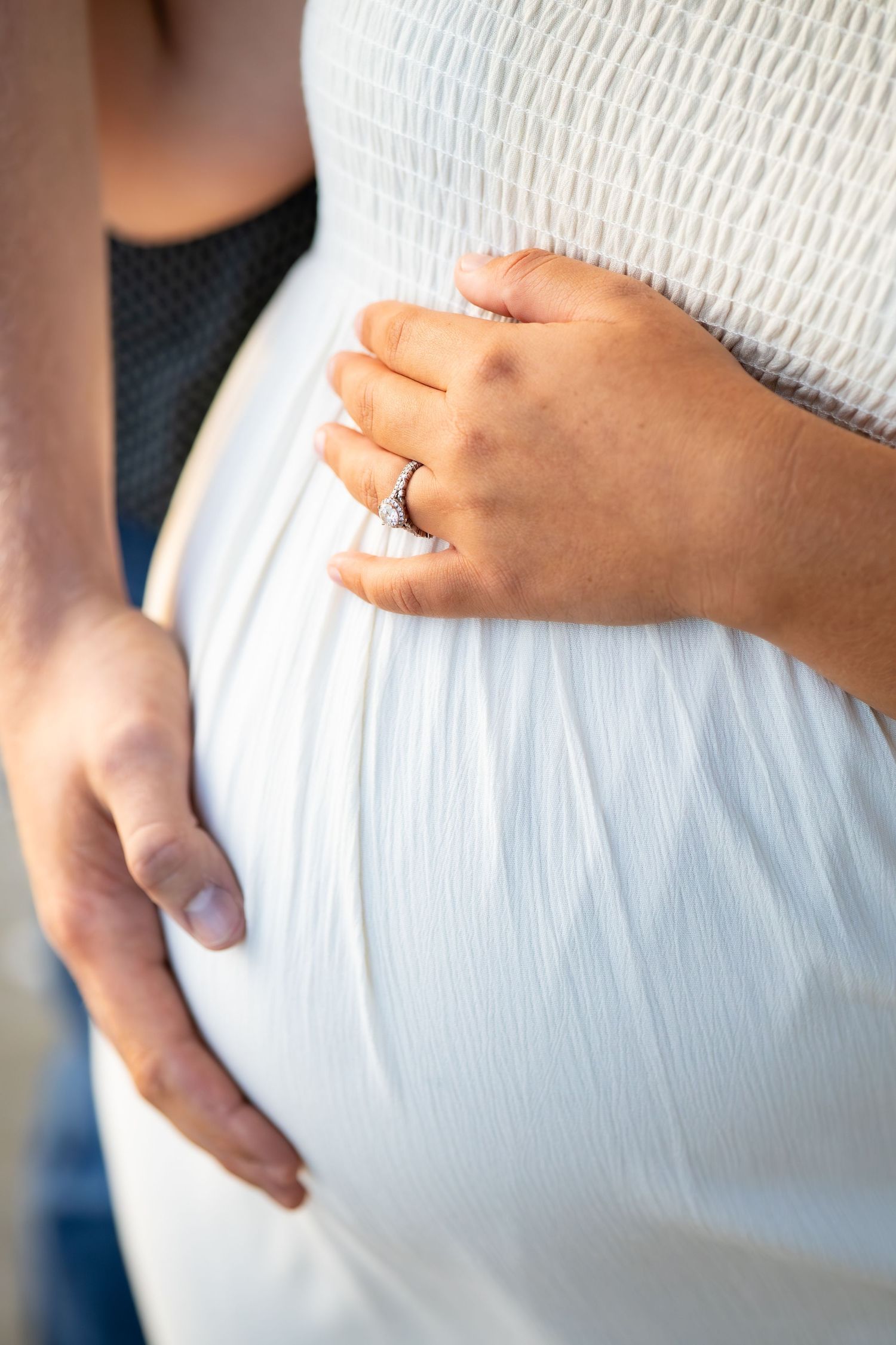 Close-up sequence of hands gently cradling a white fabric covered pregnant belly, showing progression of tender moments.