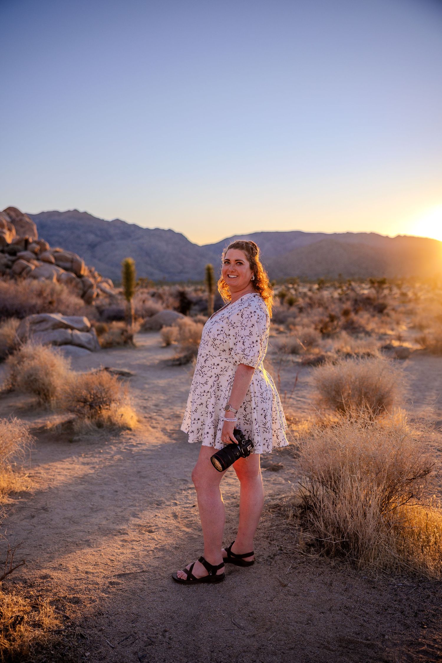 Desert landscape at sunset with cacti and mountains framing a portrait session.