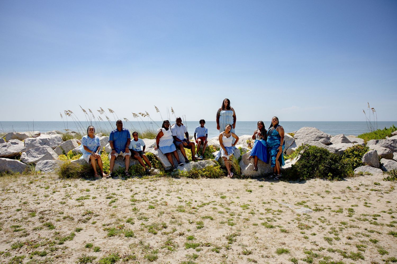 Group sits together on coastal rocks with ocean and seabirds in the background.