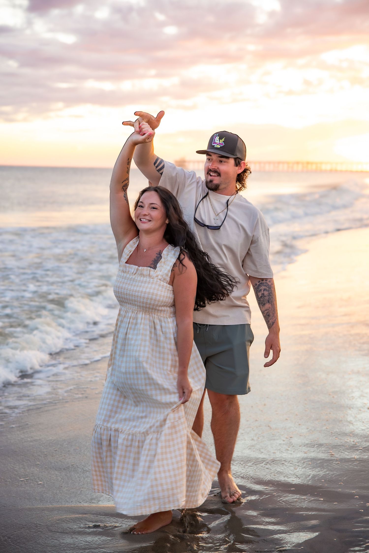 Couple dancing together on beach at sunset with waves rolling in.