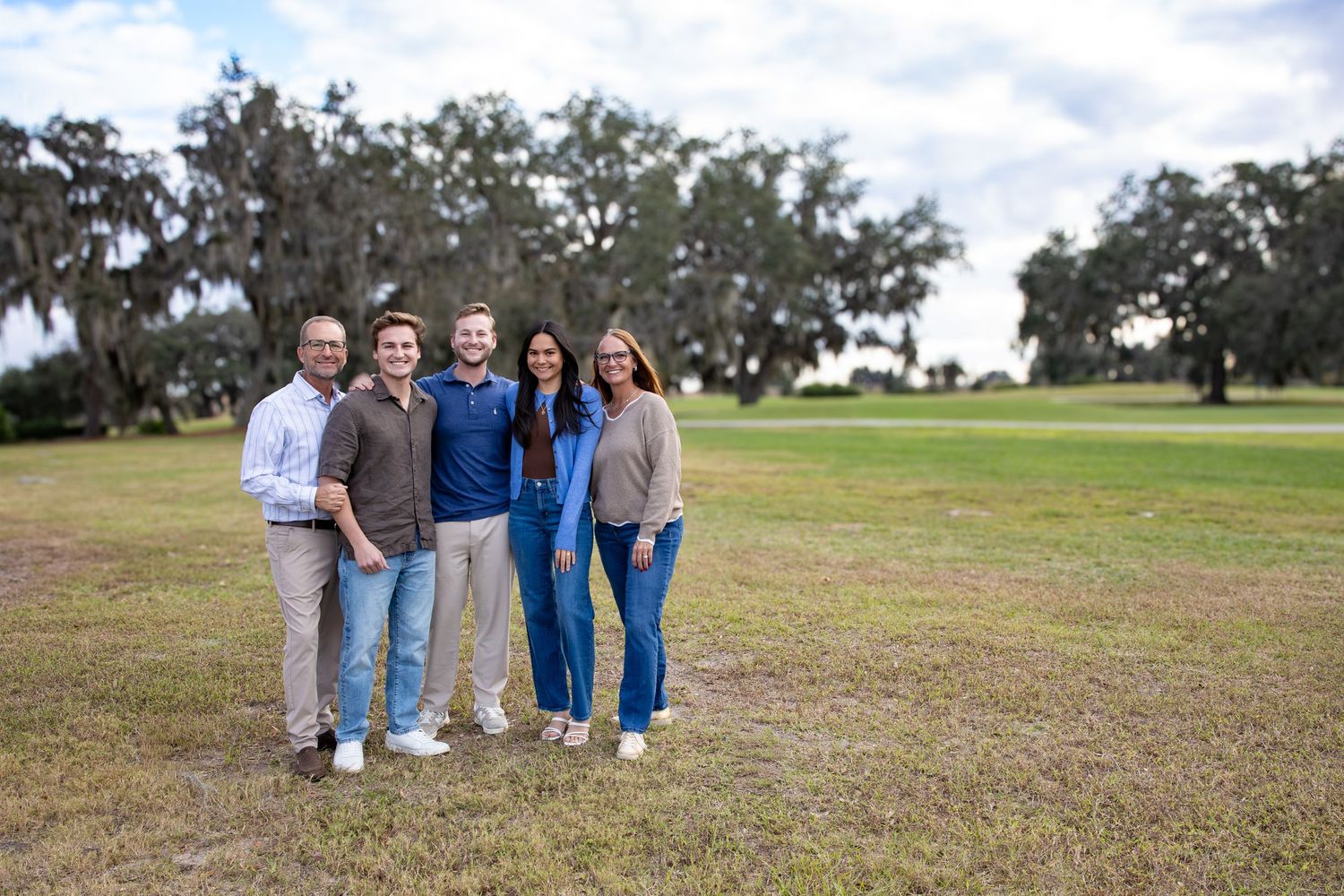 Wide landscape shot of family group posing in grassy field.