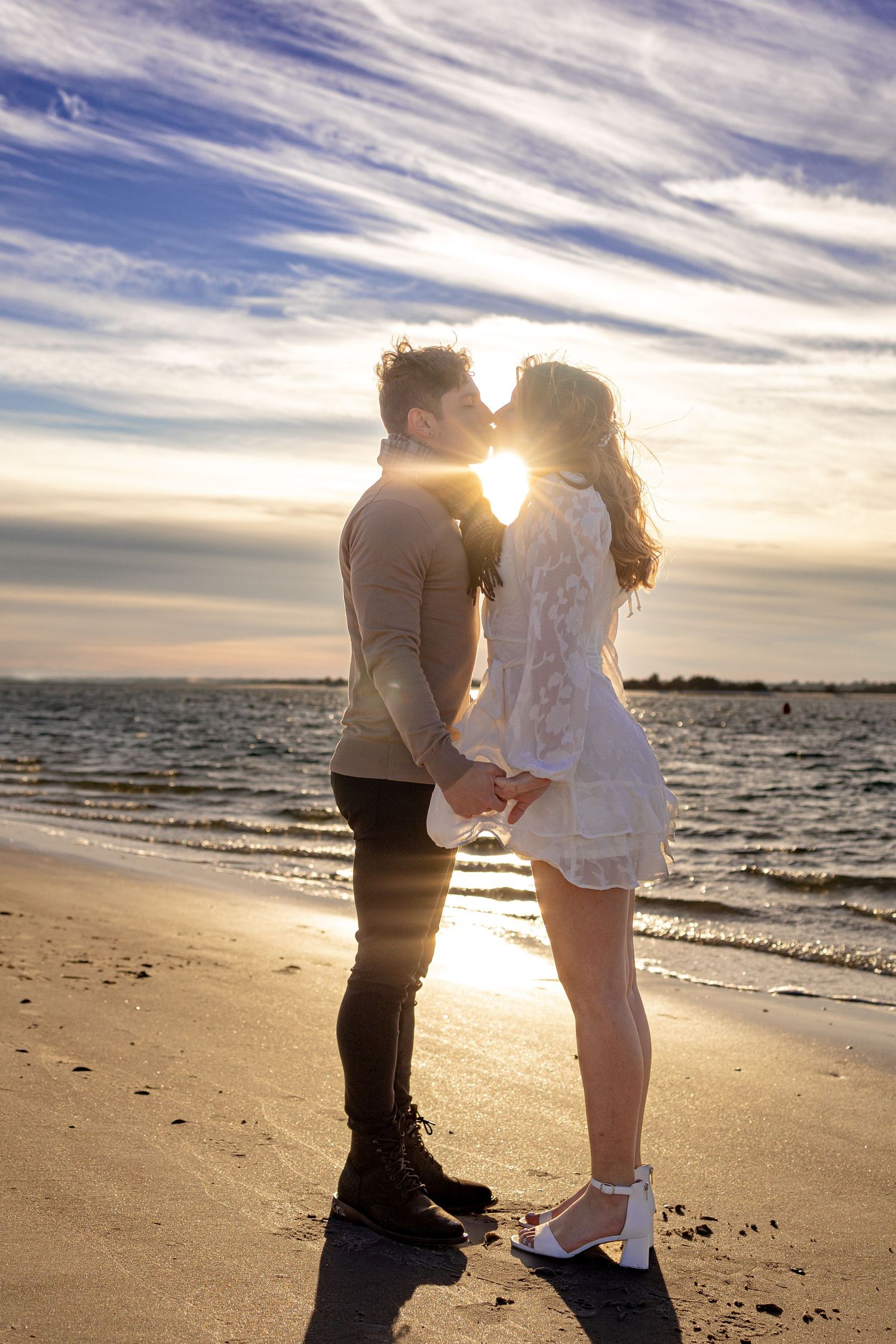 Romantic beach proposal at sunset with dramatic cloud formations and ocean views.