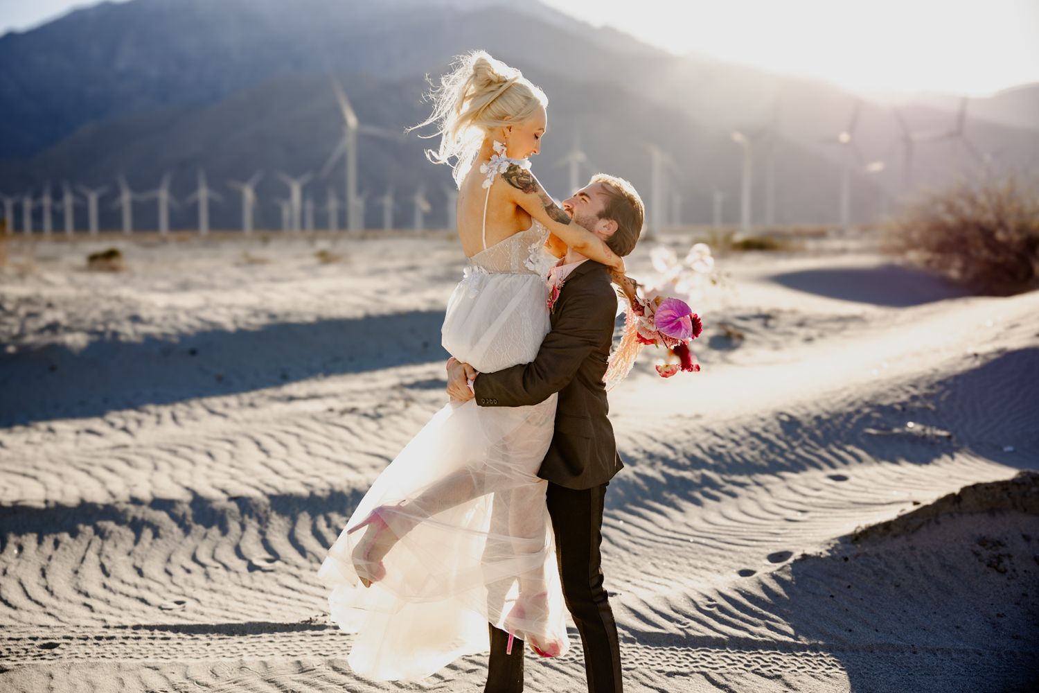 Beach wedding portraits with dramatic lighting and sand patterns in the foreground.