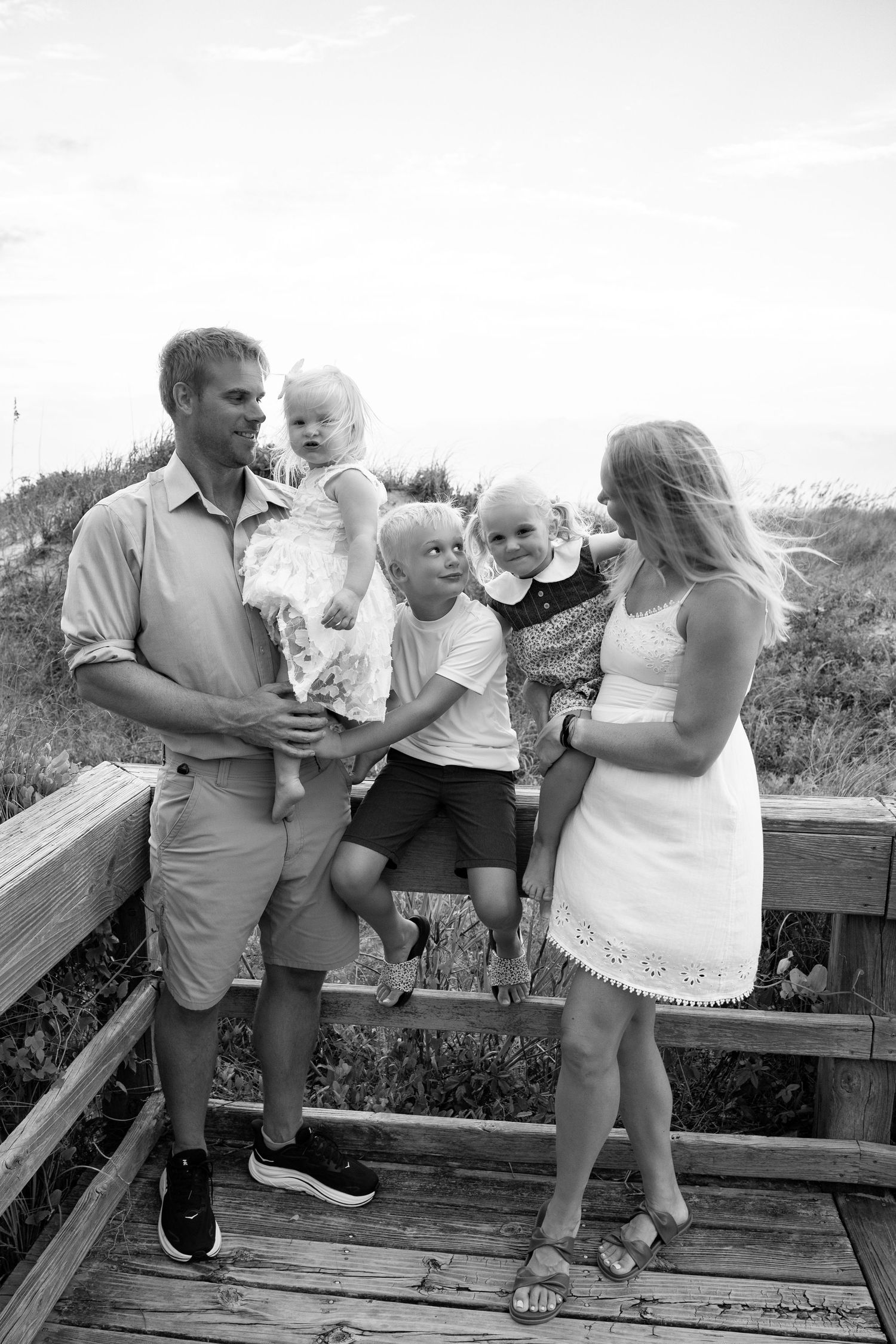 Black and white family portrait on a wooden boardwalk overlooking natural scenery.