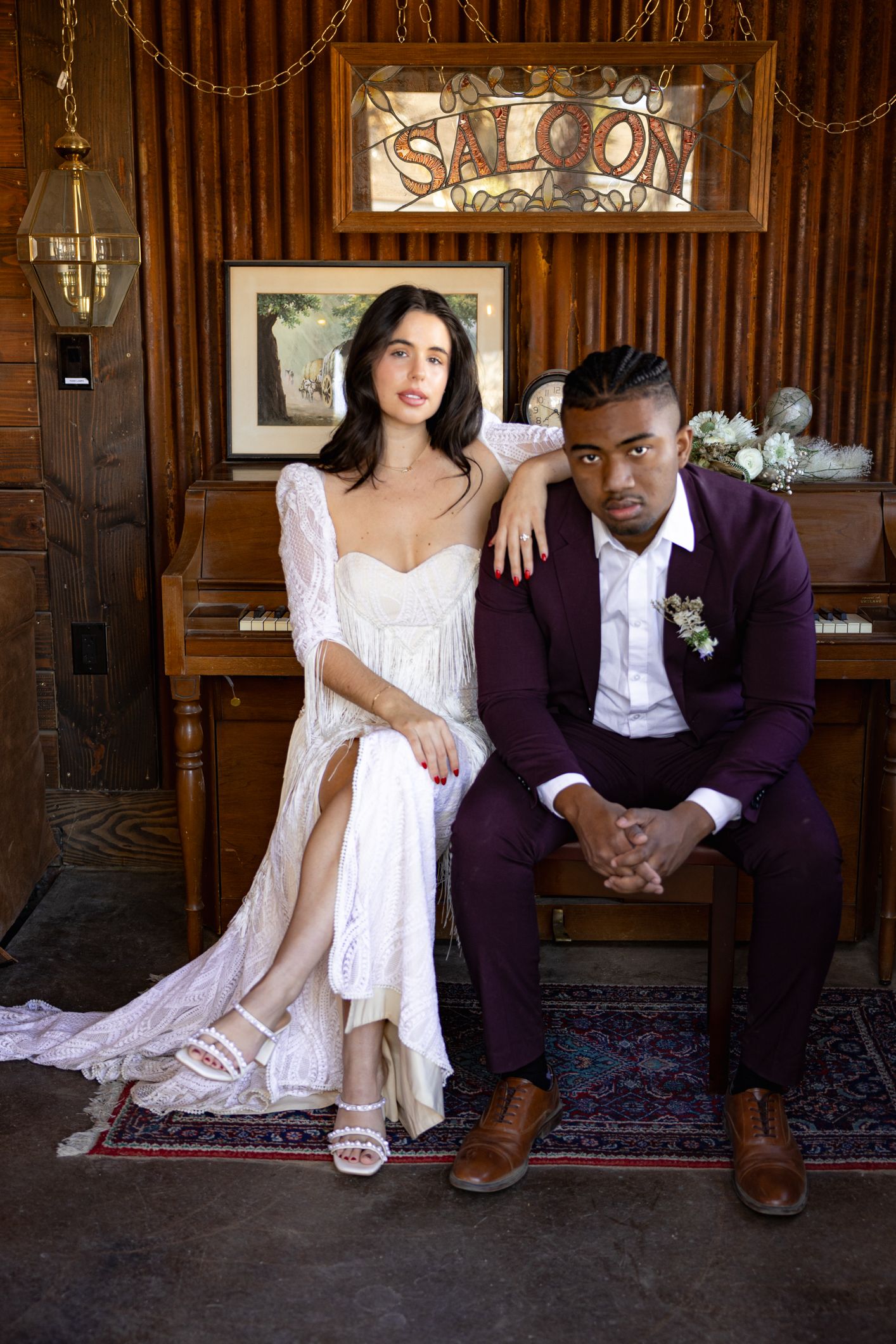 Elegant wedding couple in rustic venue with saloon sign and vintage decor.