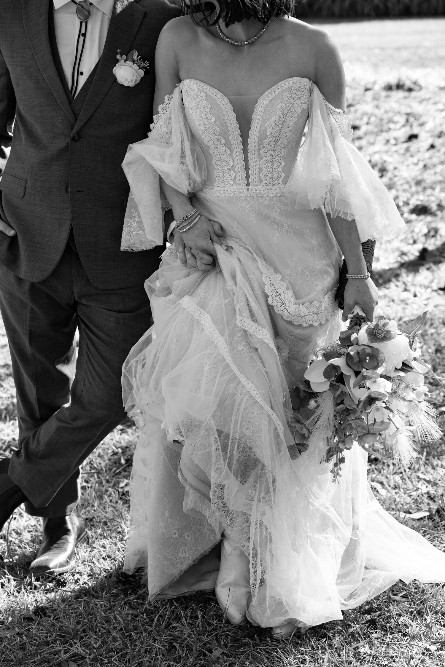 Black and white detail shot of an elegant wedding dress with delicate lace and flowing tulle fabric.