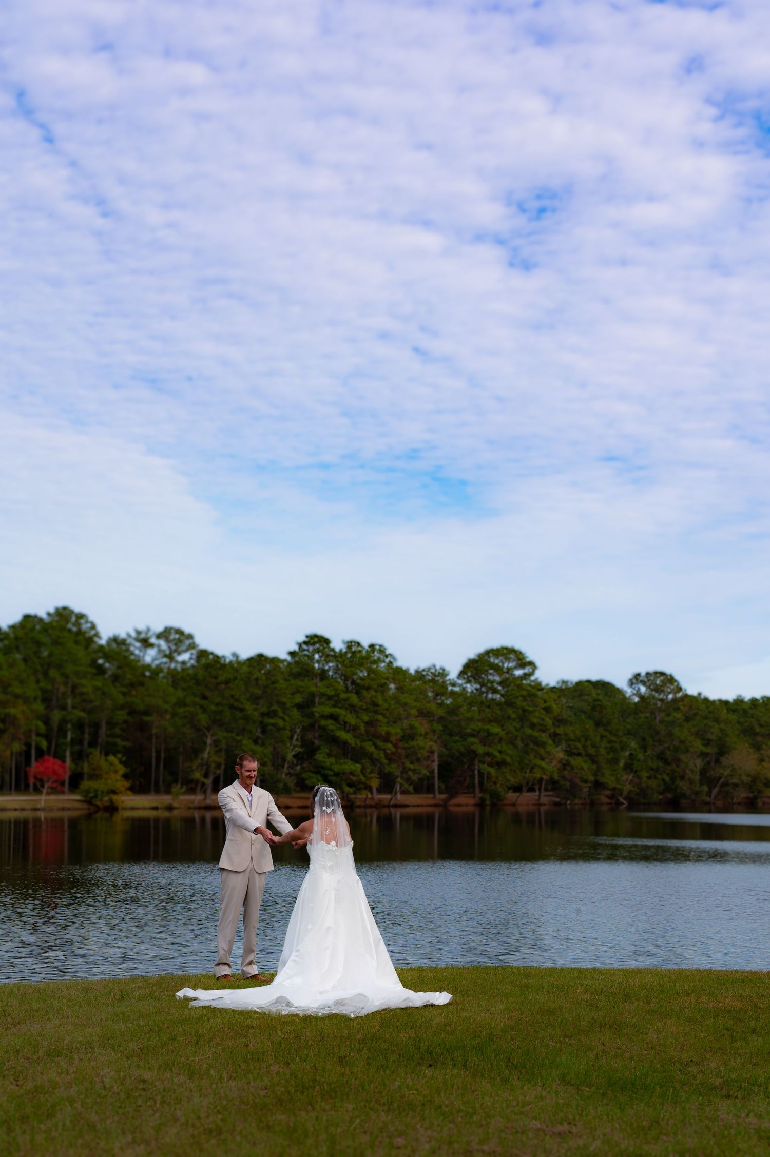 A scenic lakeside wedding photo with pine trees and blue skies in the background.