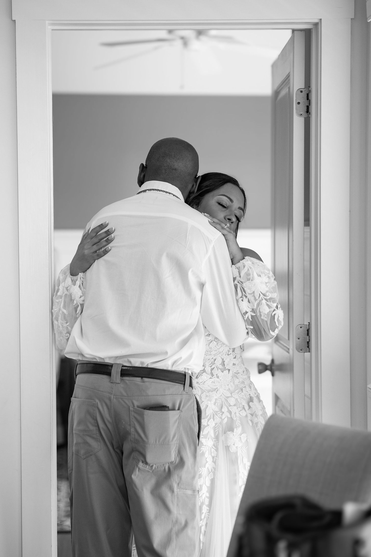 A tender embrace captured in black and white showing a couple sharing an intimate moment in a doorway.