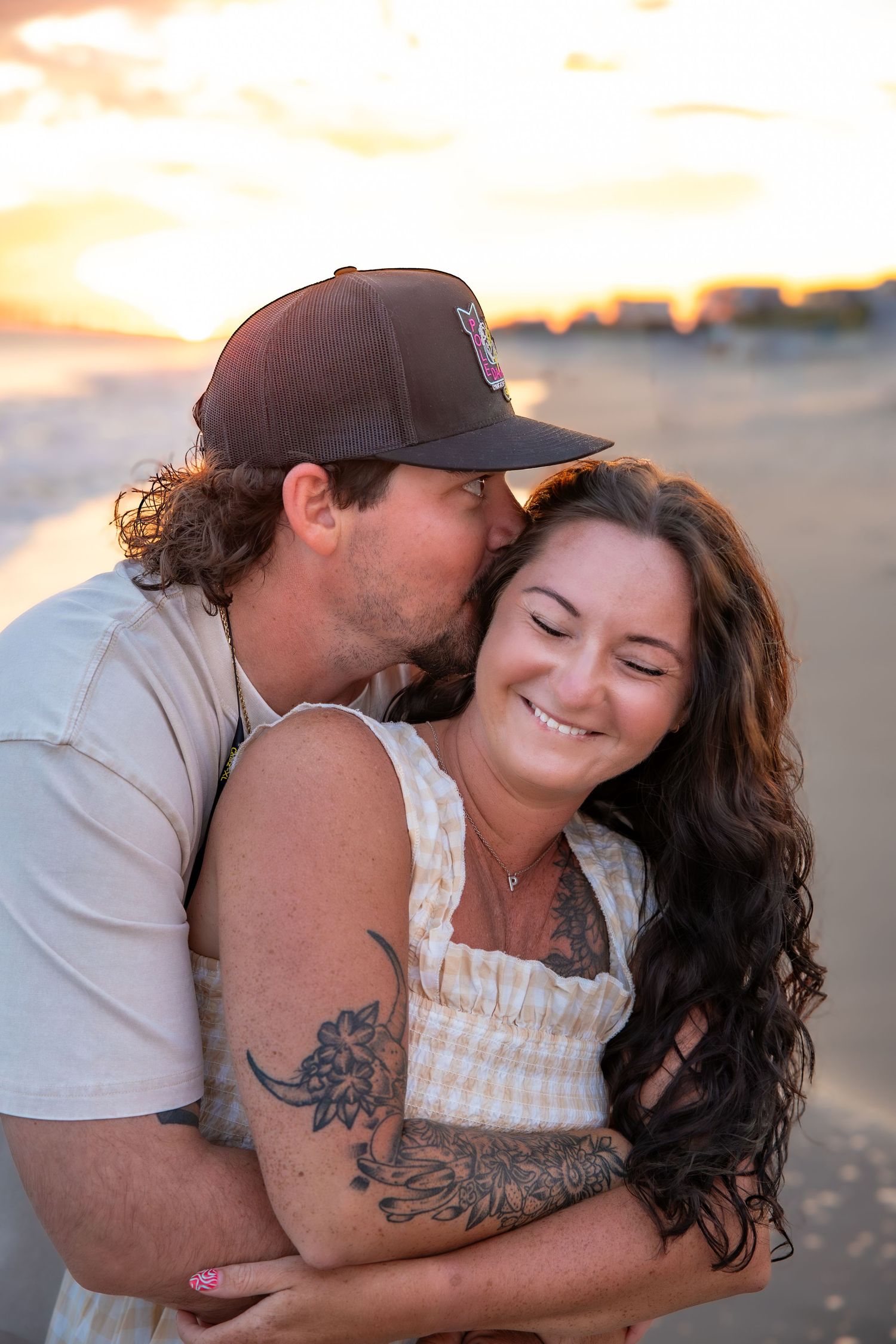 A romantic couple embraces on the beach at sunset while sharing tender moments together.
