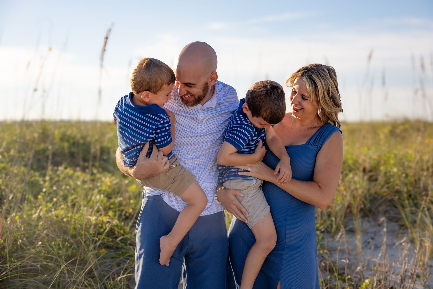 Family in coordinating blue and white outfits playing together outdoors.