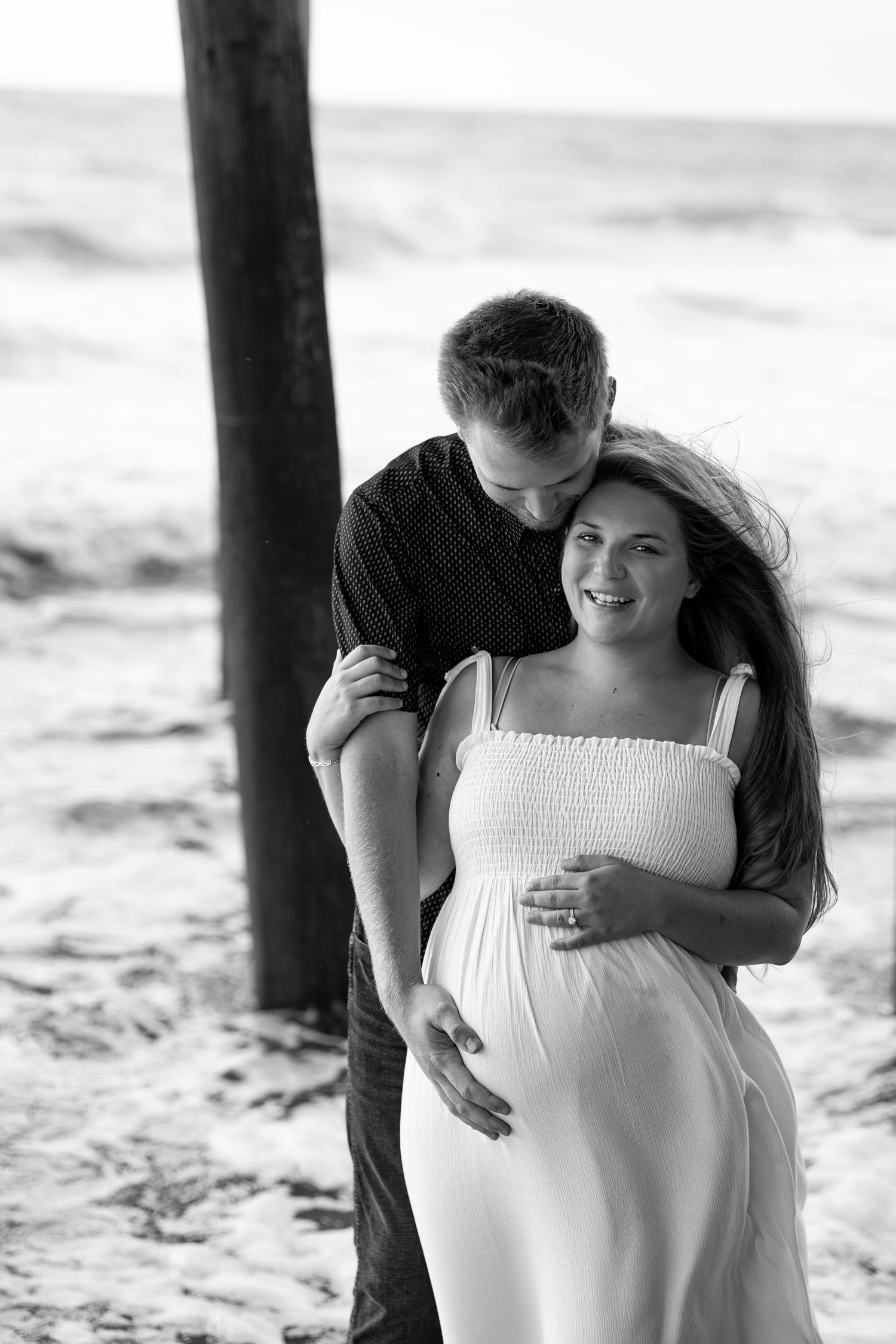 A romantic black and white beach photoshoot sequence shows a couple embracing under a pier.