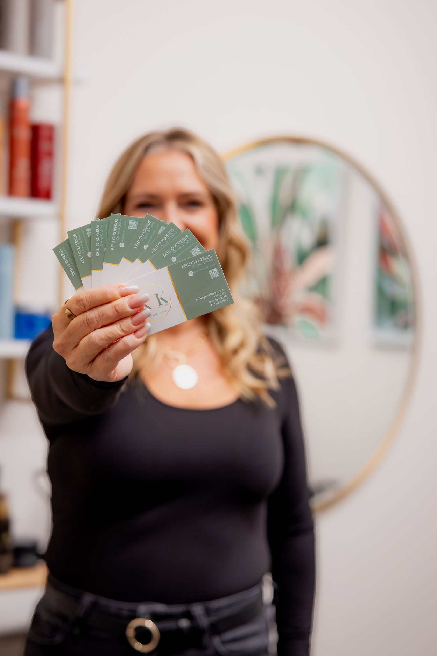 Someone holding a fan of green cards against a white wall with decorative hoops.