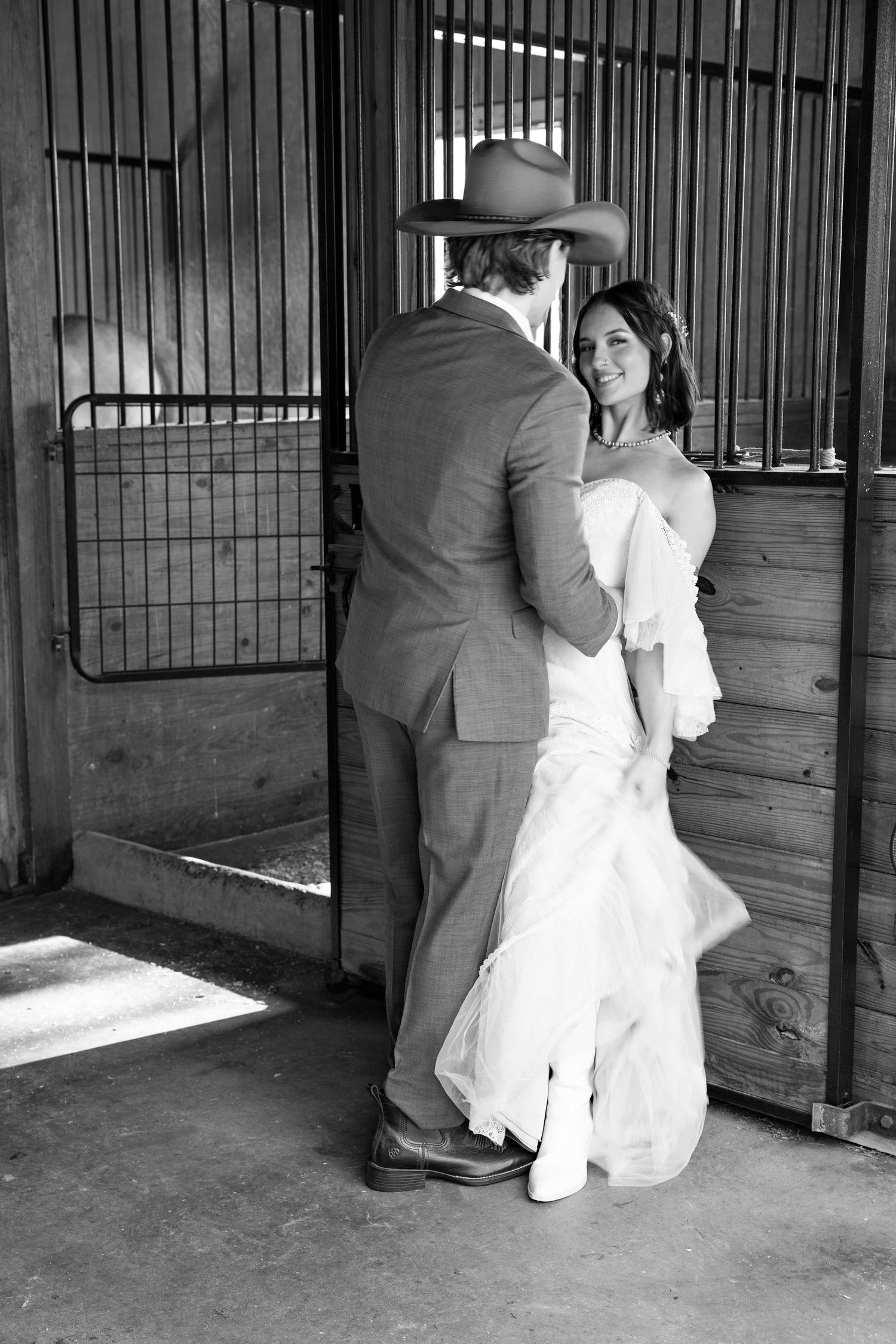 Black and white wedding photos taken in rustic stable setting.