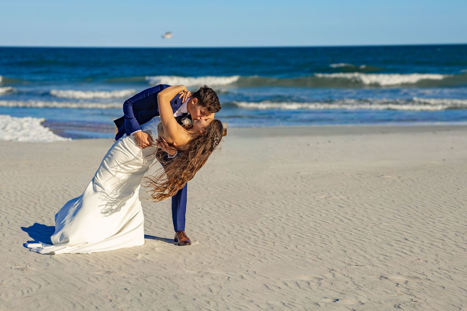 A romantic beach wedding photoshoot with waves crashing in the background.