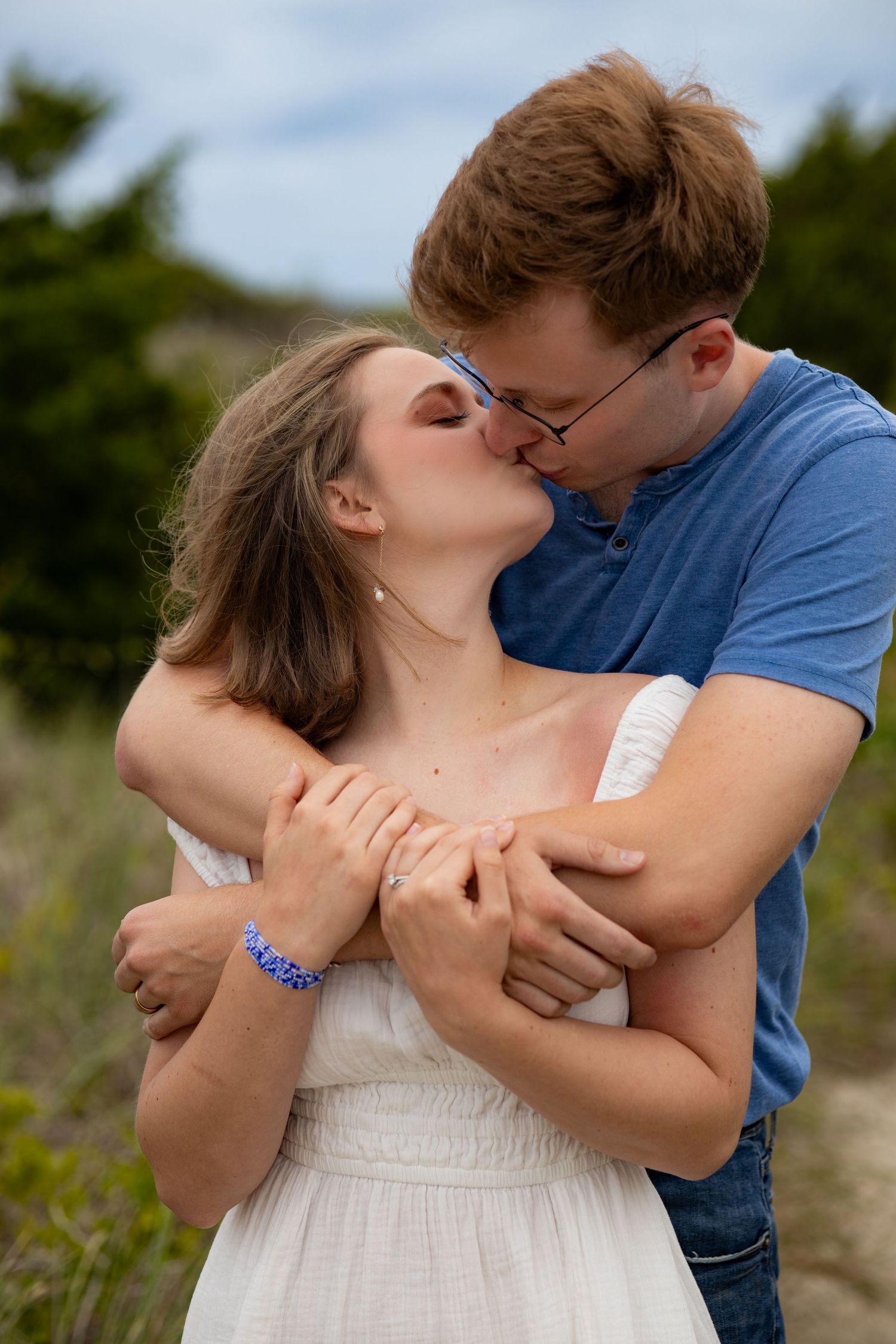 Romantic couple in a white dress and blue shirt sharing intimate moments in a natural outdoor setting.