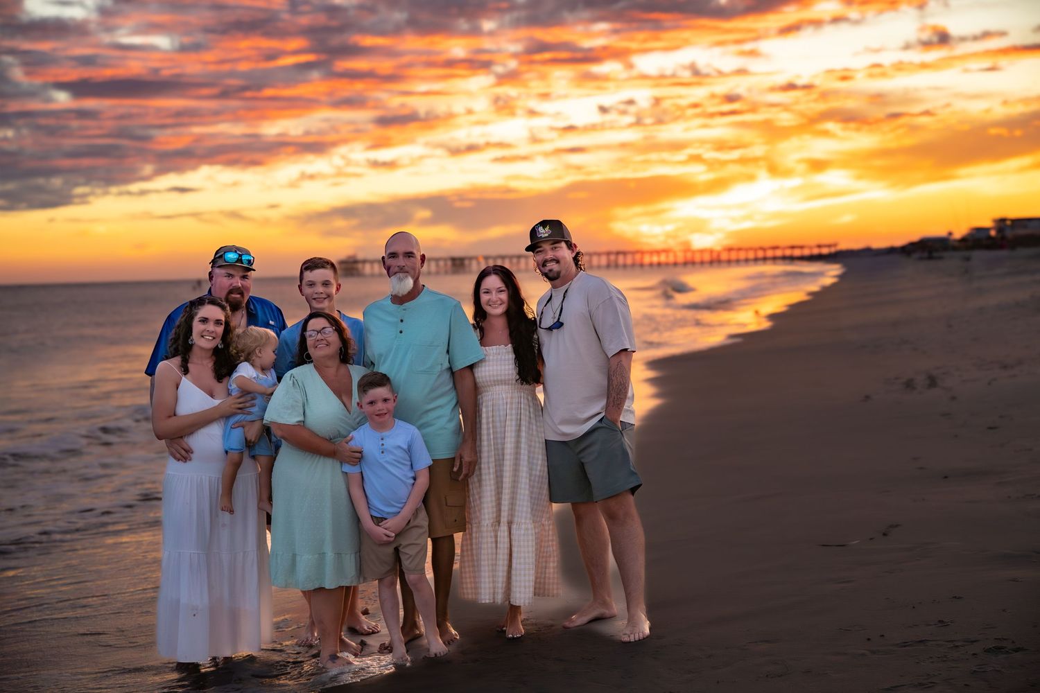 Group portrait on beach at sunset with dramatic orange sky.