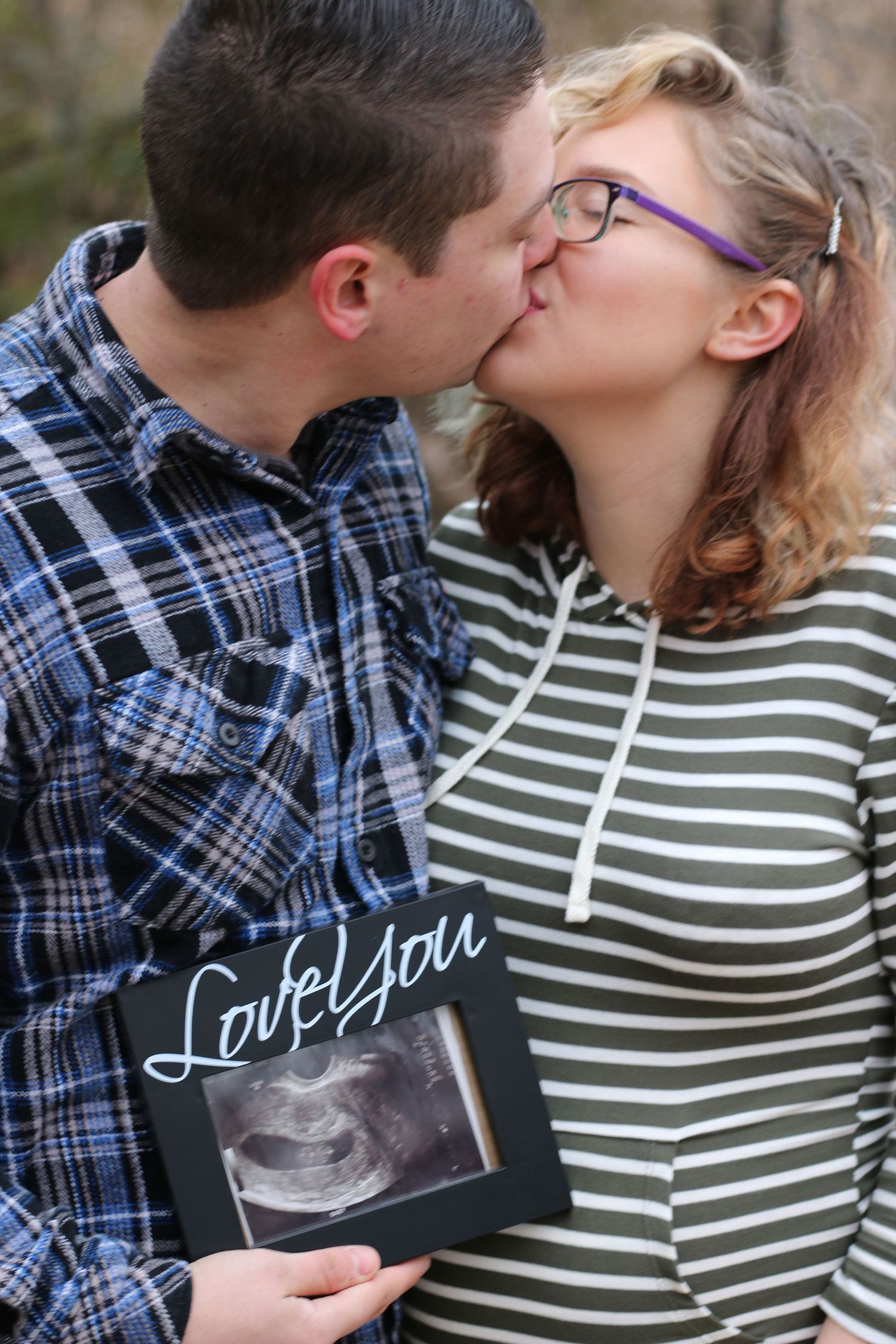 Couple sharing intimate moment while holding ultrasound photo.