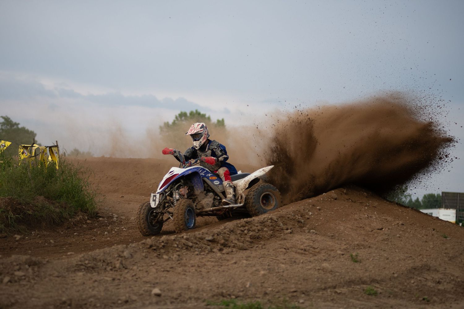 ATV riders racing through dirt trails creating dramatic dust clouds.