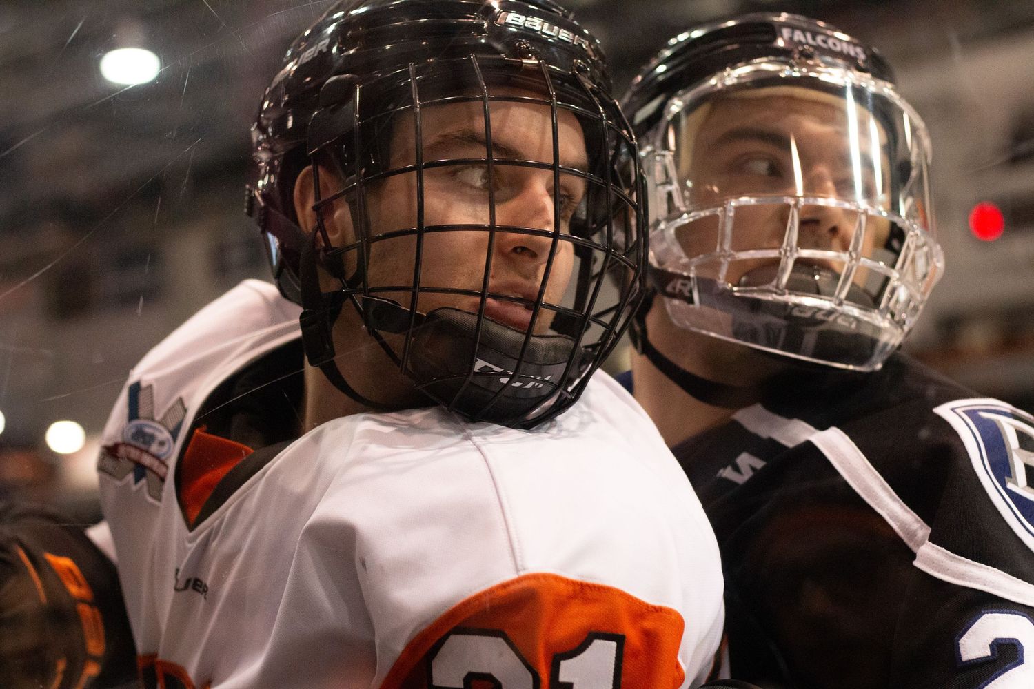 Hockey players in white and orange jerseys collide during intense game action.