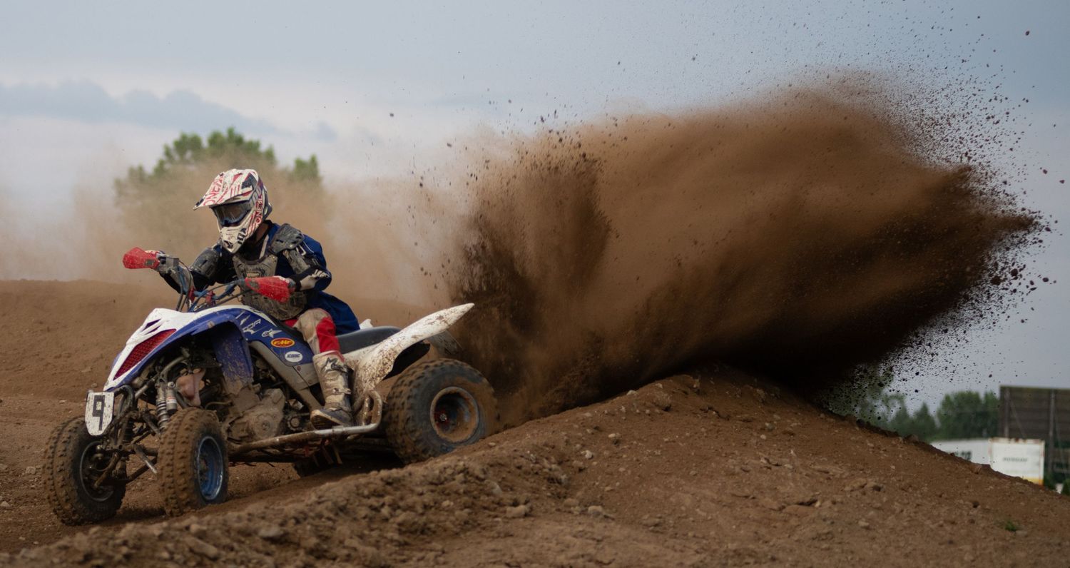 Motocross riders creating dramatic rooster tails of dirt on an off-road racing track.