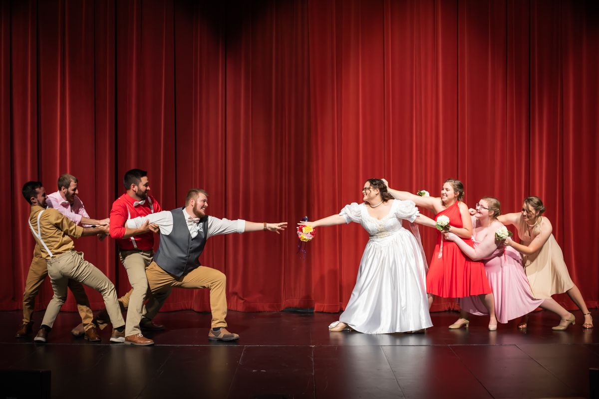 Bridal party attempts to pull the bride and groom apart on stage