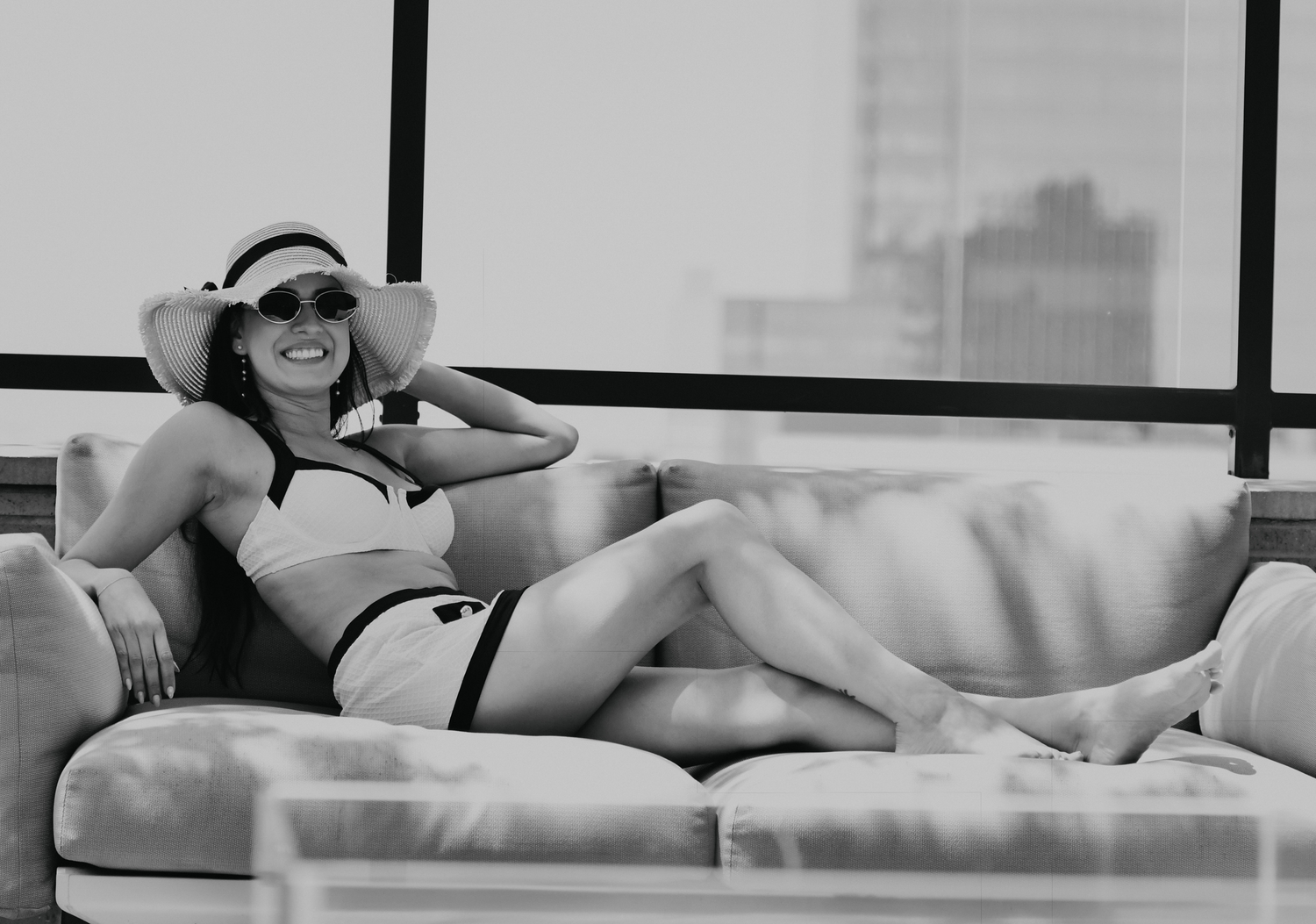 Dallas Model lounging on modern sofa with city skyline view captured by Texas photographer.