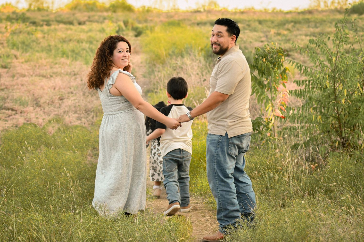 Family members dance and play together in a grassy meadow at sunset captured by Texas photographer .