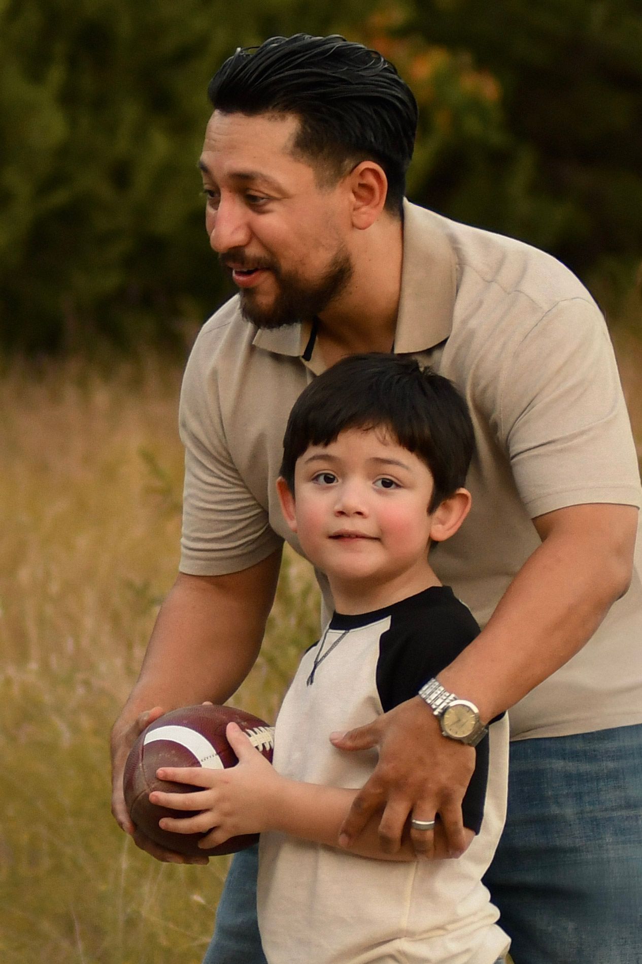 Playful father and child moments captured with a football in a golden field.