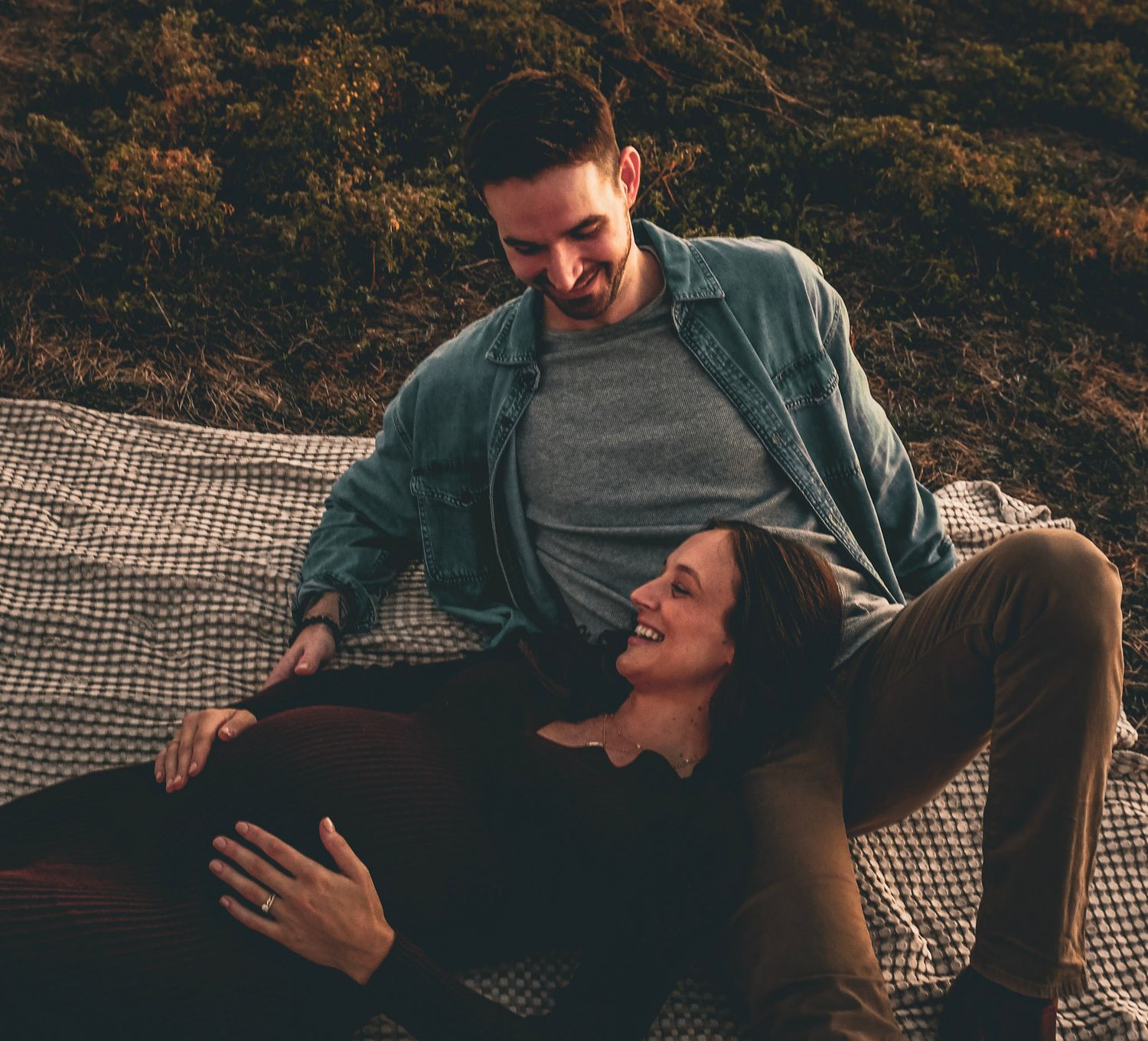 Couple sharing a joyful moment while relaxing on a picnic blanket at sunset captured by Texas photographer