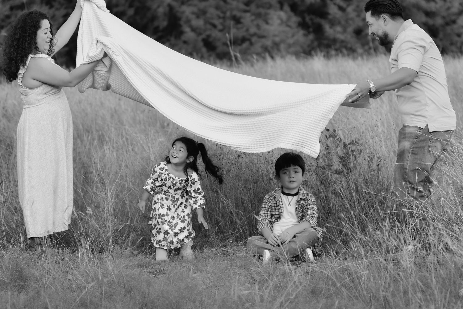 Texas photographer captures family picnic with a flowing blanket creating ethereal movement in an outdoor family photoshoot.