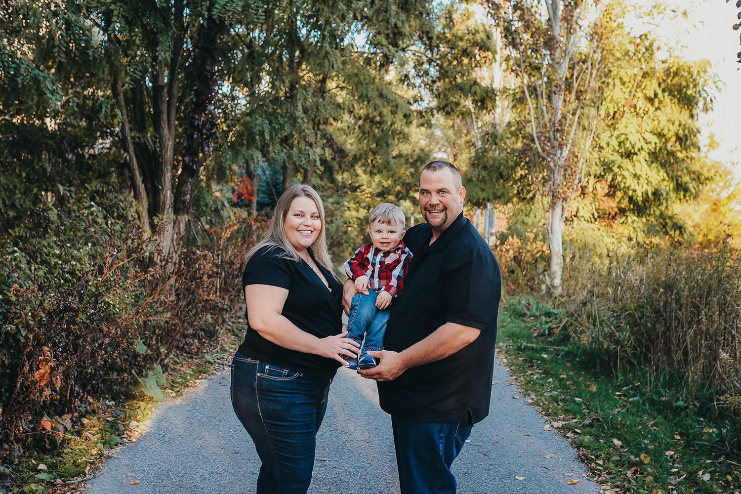 Family walking together on nature trail during golden hour.