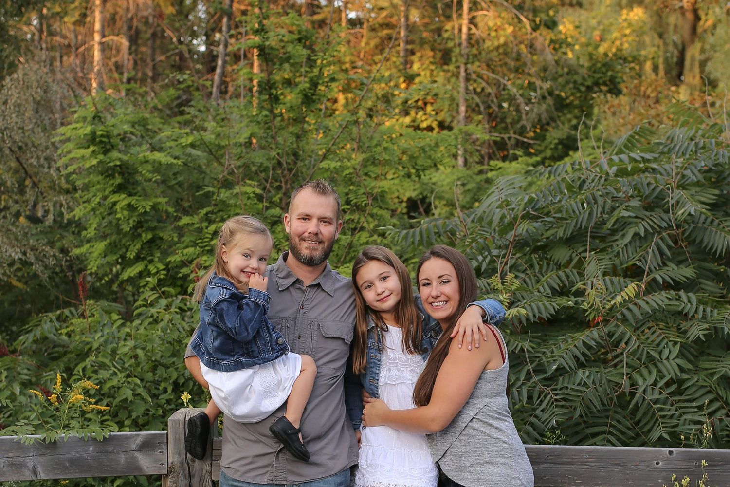 Family embracing outdoors surrounded by lush green foliage.