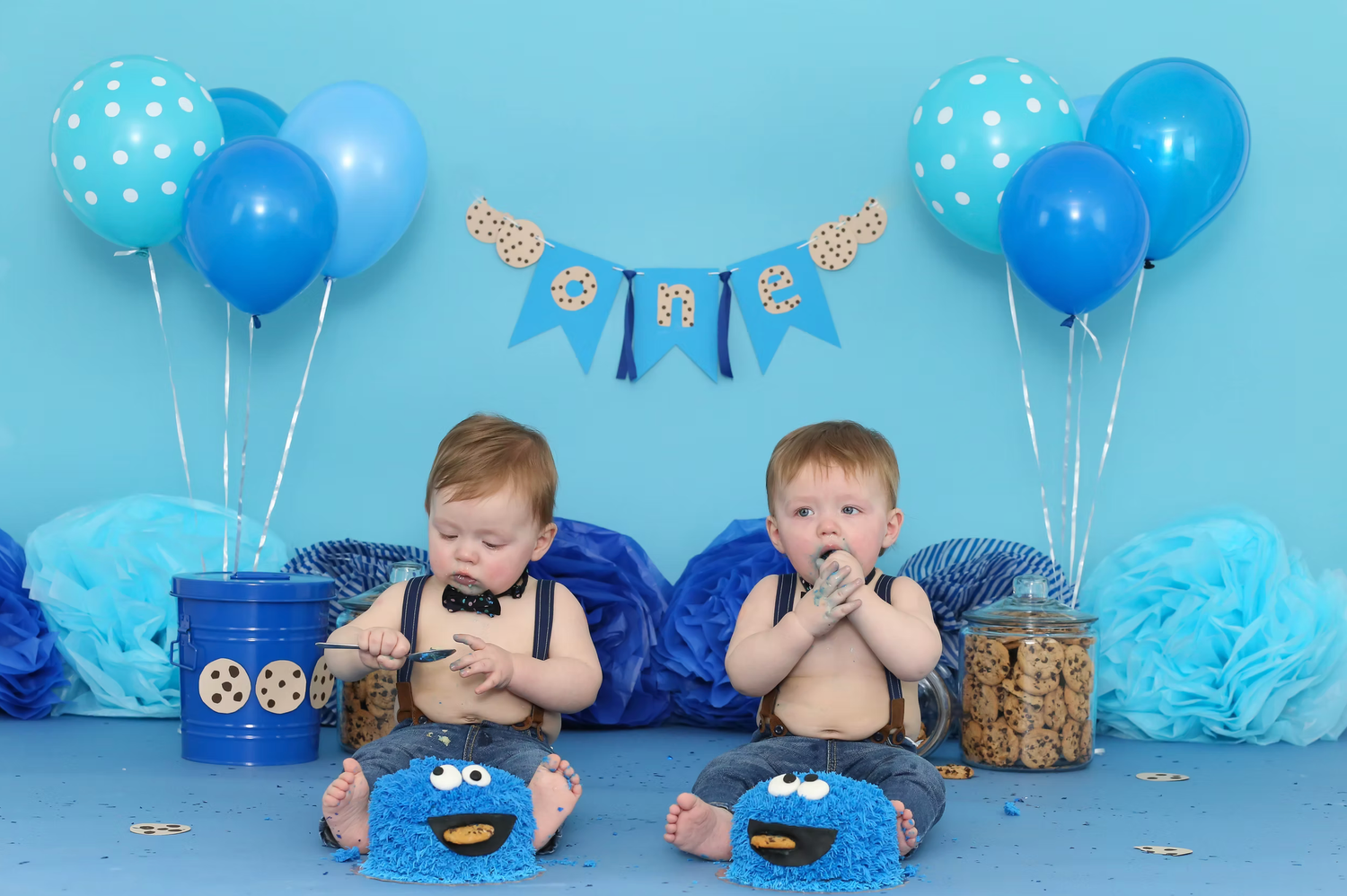 Blue themed cake smash setup with polka dot decorations and Cookie Monster inspired elements.