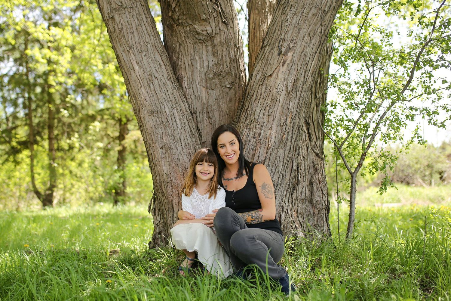 Outdoor portrait session against large tree trunk in natural lighting.