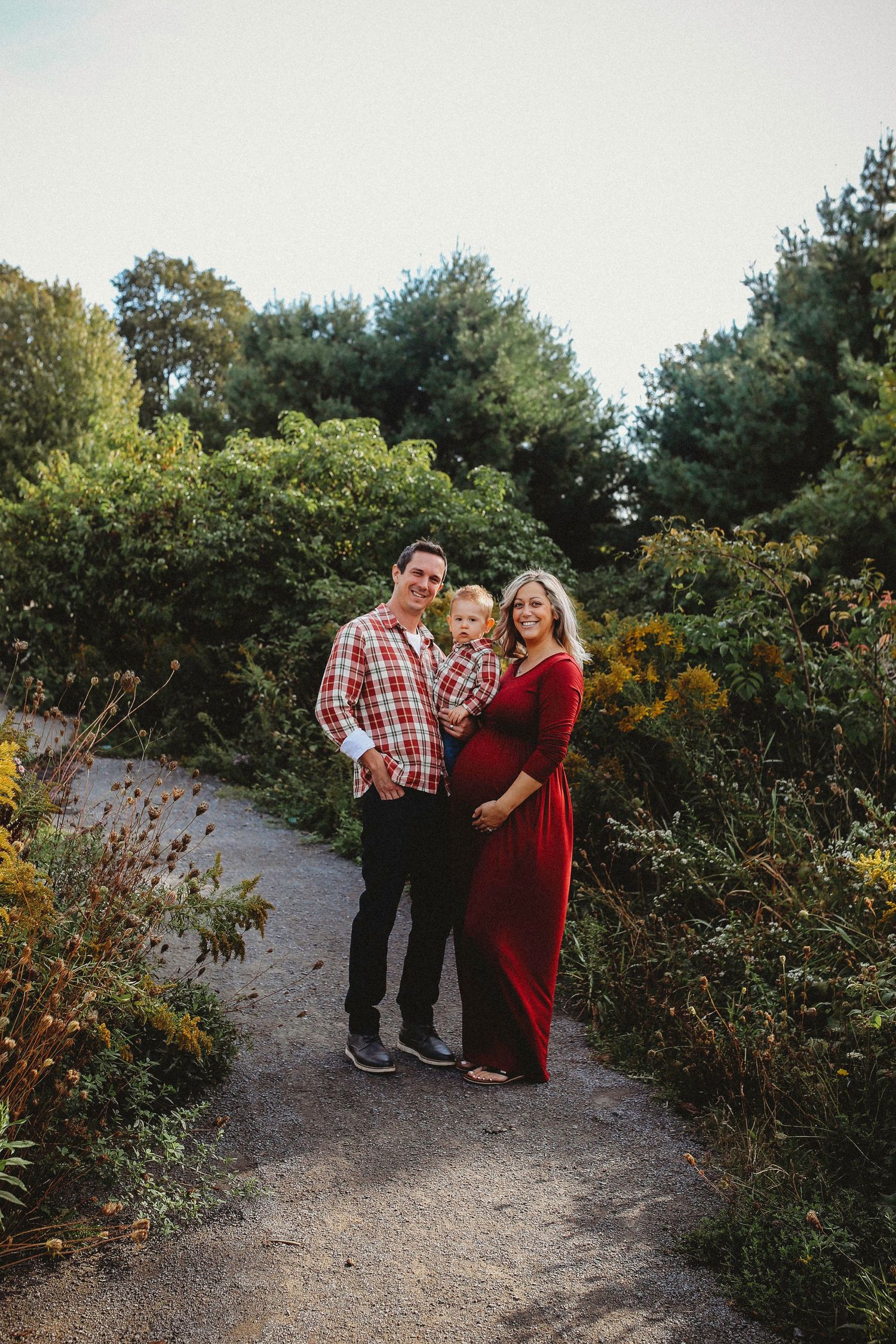 Couple walking together on a nature trail surrounded by autumn foliage and evergreen trees.