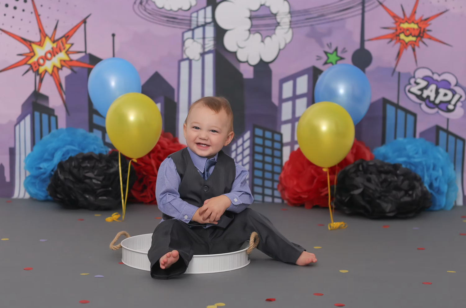 Colorful superhero themed cake smash setup with balloons and decorative backdrop.
