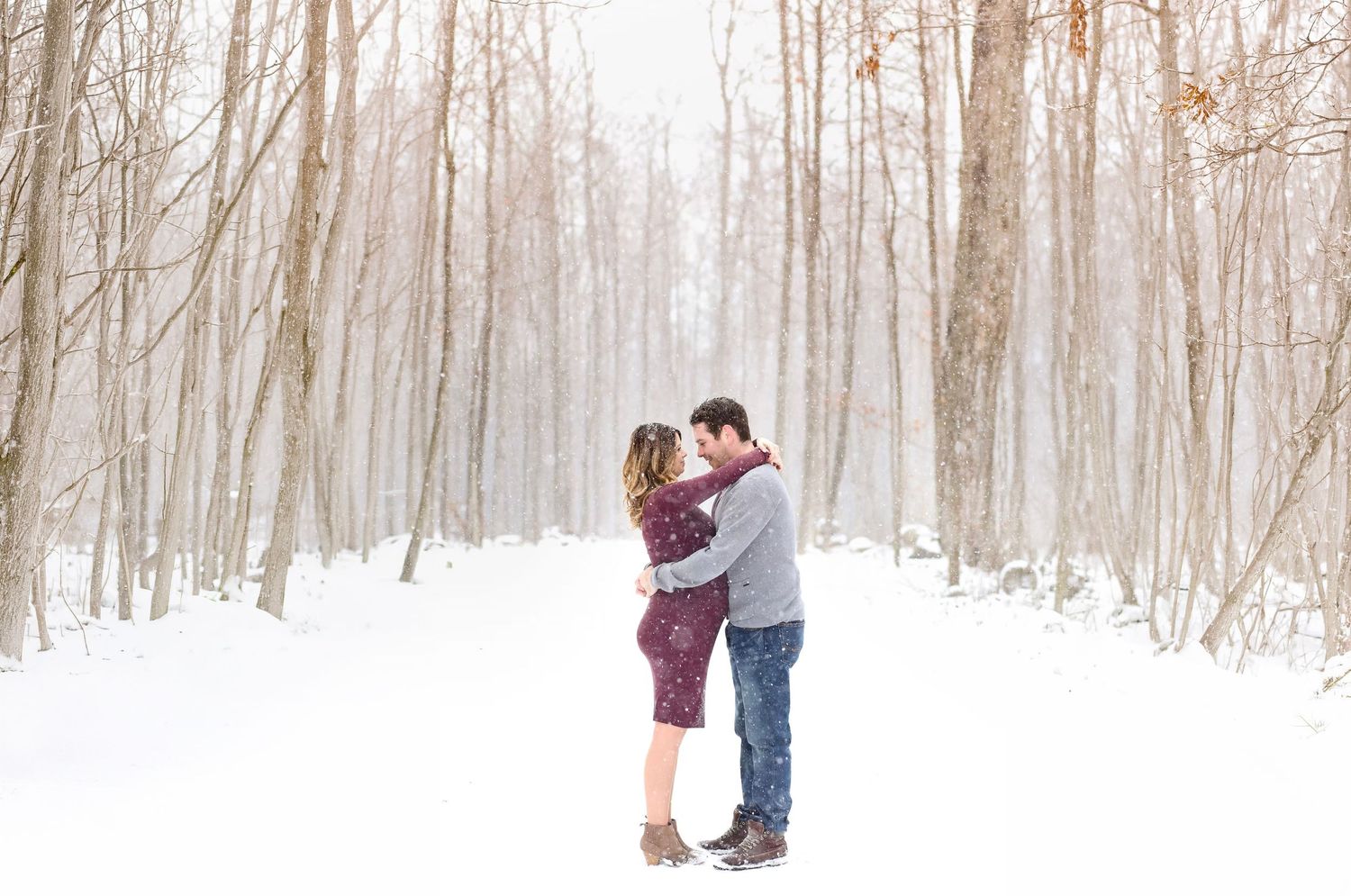 A snowy winter forest scene with tall bare trees creating a misty atmosphere.